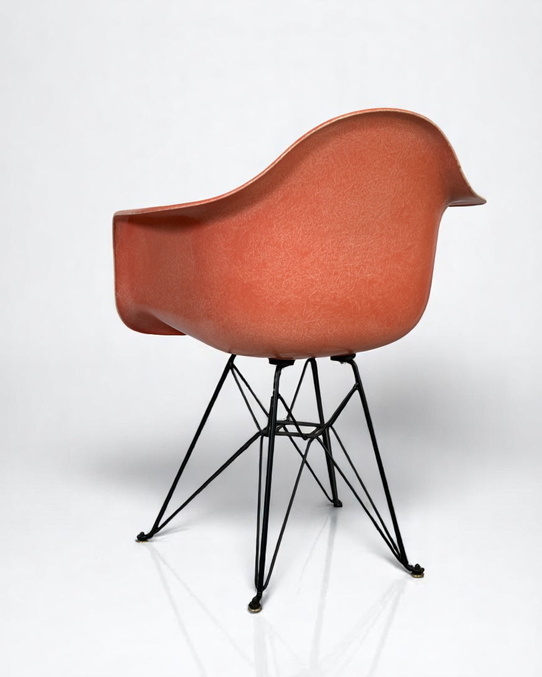 Modernica Case Study Furniture Arm Shell Eiffel chair, pre-owned, in color coral, with black metal base.