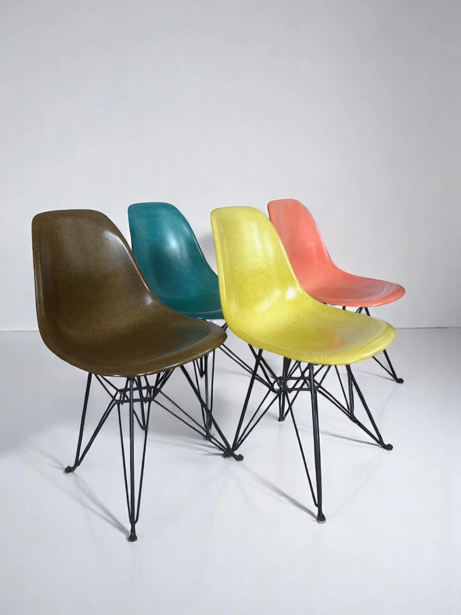 Pre-owned, Modernica Case Study Furniture Side Shell Eiffel, set of 4 chairs in colors pickle, coral, peacock, and pumpernickel with black metal bases.