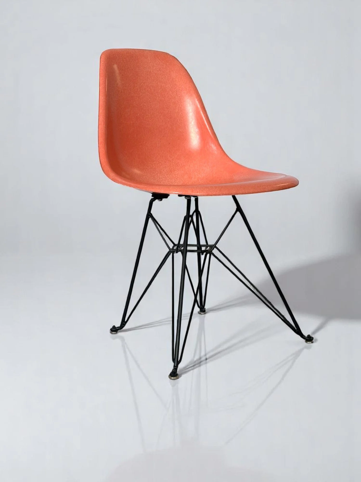 Pre-owned, Modernica Case Study Furniture Side Shell Eiffel chairs in color coral with black metal base.