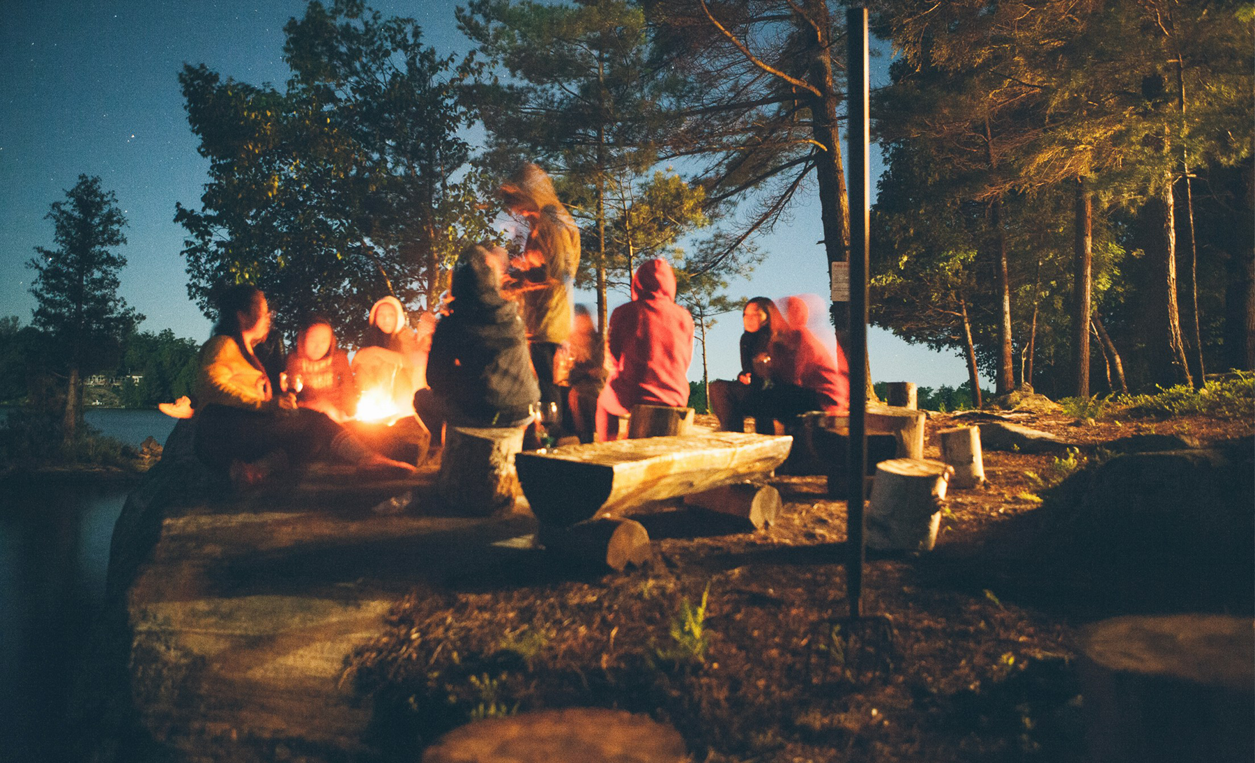 A team of colleagues gathered around a firepit during a team building retreat