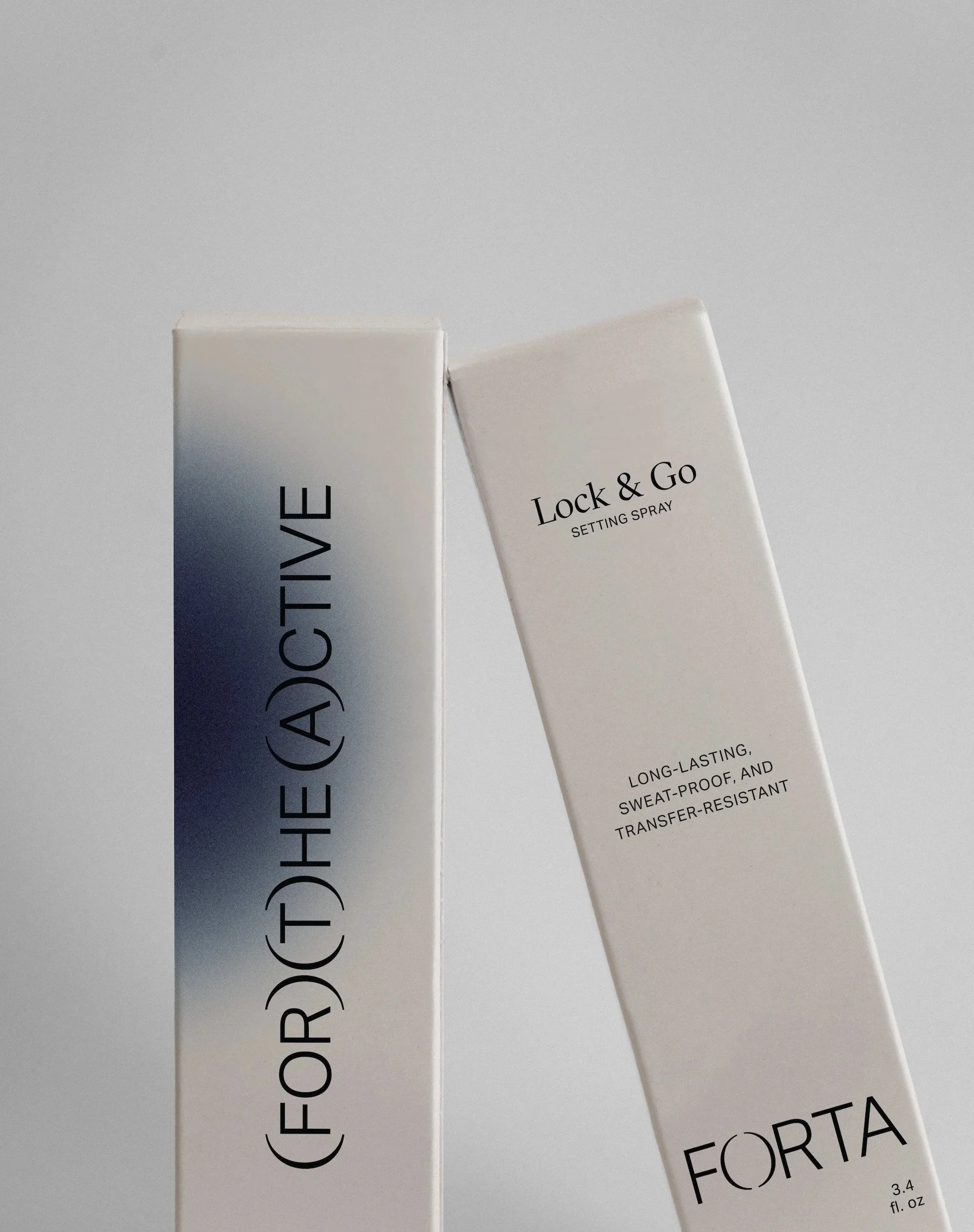 Two white rectangular boxes of cosmetic spray product, one labeled 'FOR (D)HE (A)CTIVE' and the other labeled 'Lock & Go Setting Spray' with additional description 'Long-lasting, sweat-proof, and transfer-resistant'.