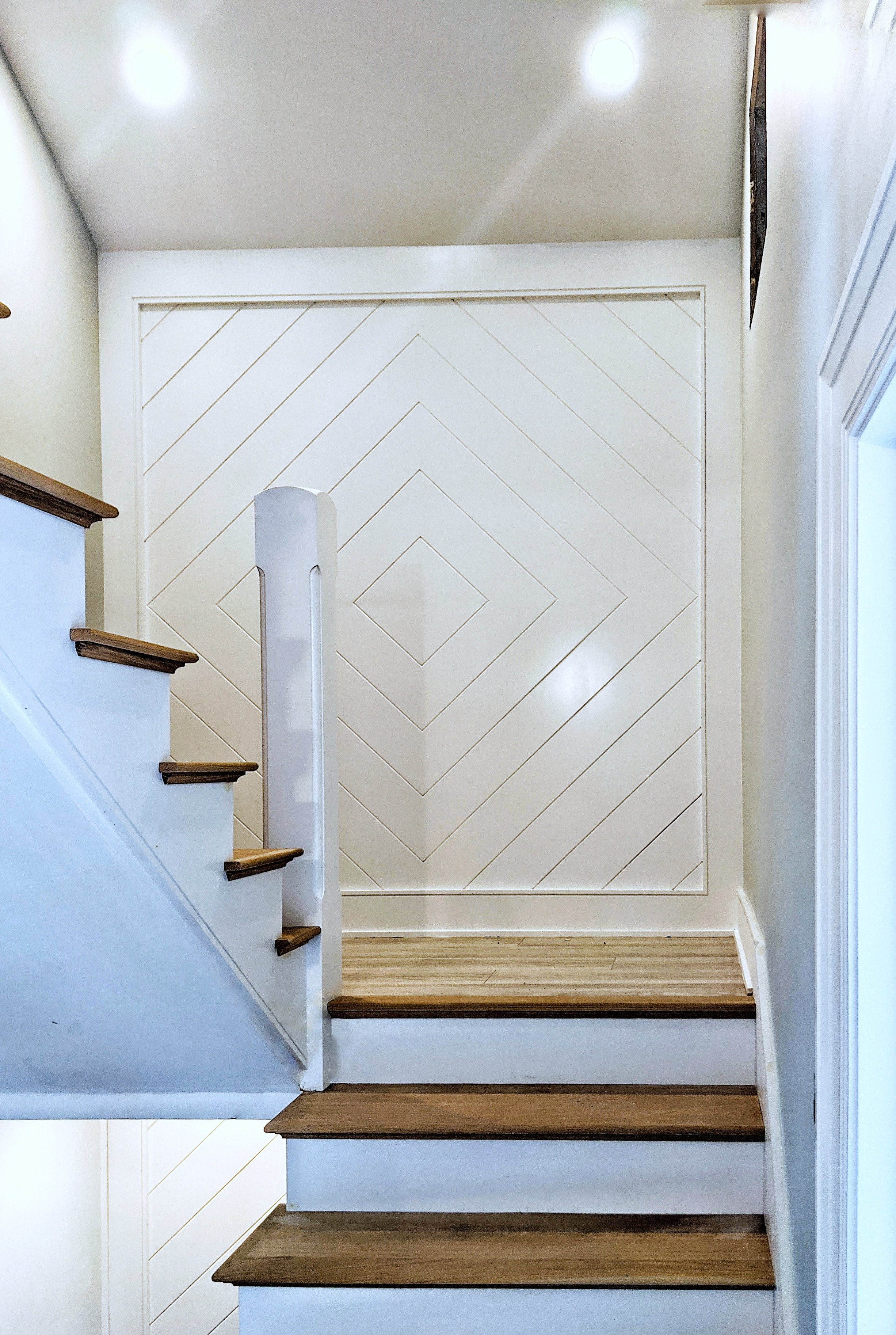 Staircase with wooden steps and a decorative wall panel with geometric patterns.