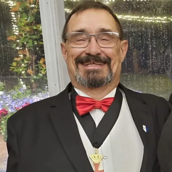 Coat of arms featuring a shield with a red cross, surrounded by angels, topped with a crown, and flanked by black and white banners. A banner below reads 'non nobis dominie nobis'.