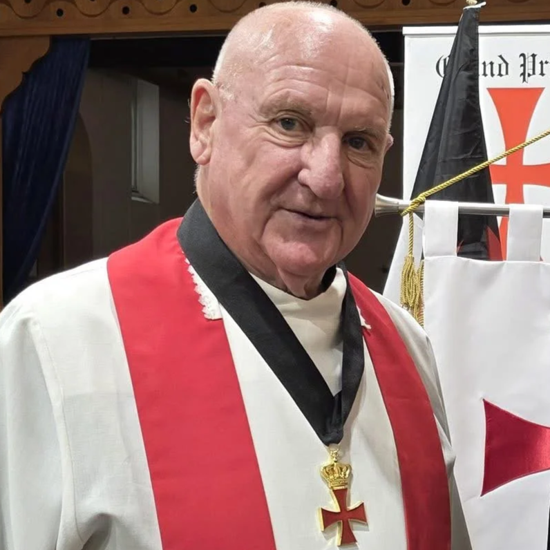A detailed coat of arms featuring a crown, shield with a red cross, angels, various flags, and Latin inscription 'non nobis domini nobis' on a scroll.