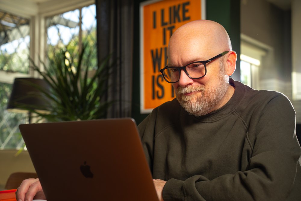 Environmental portrait of a man working on a laptop indoors with natural light