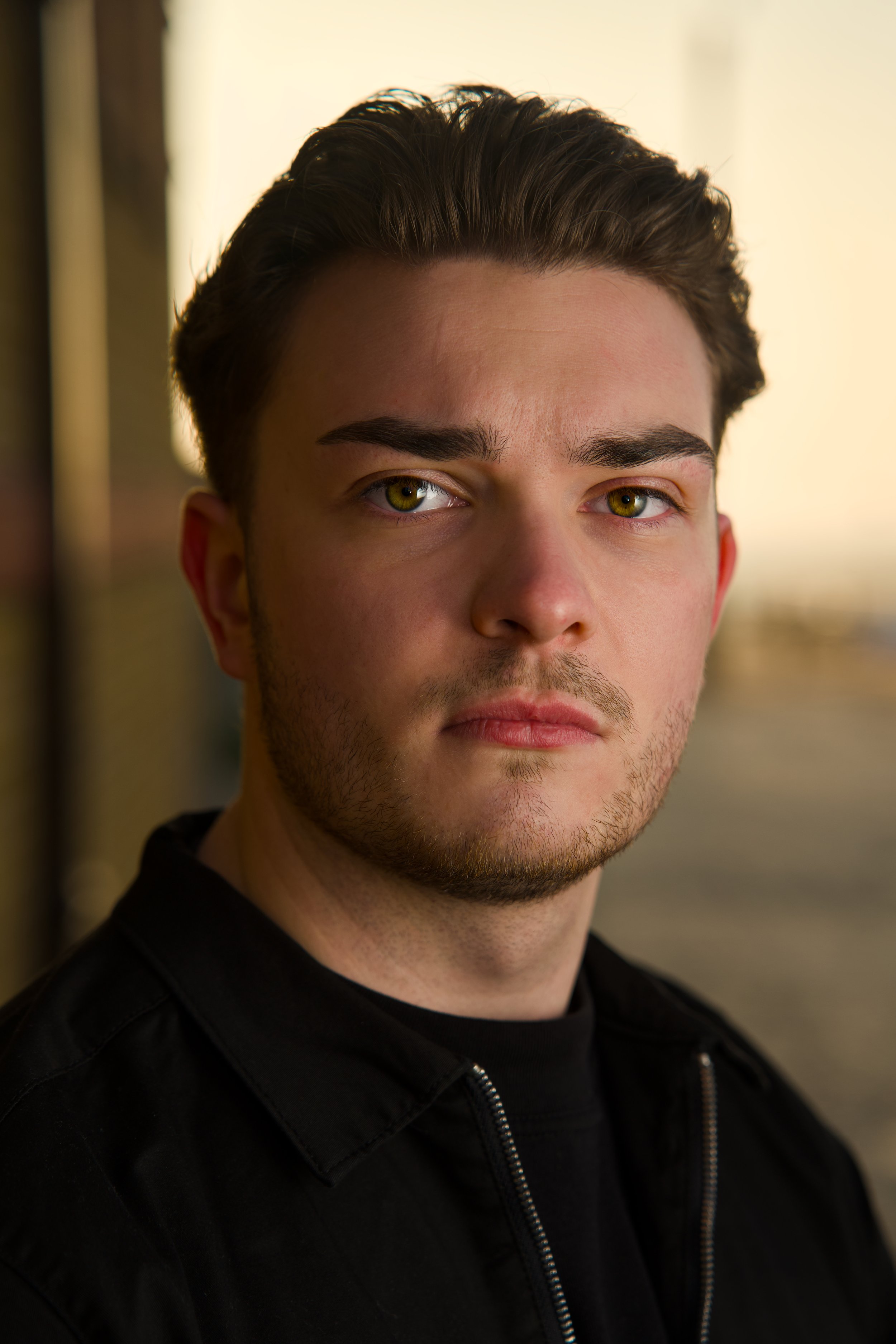 Close-up portrait of a man with short dark hair against a softly lit background