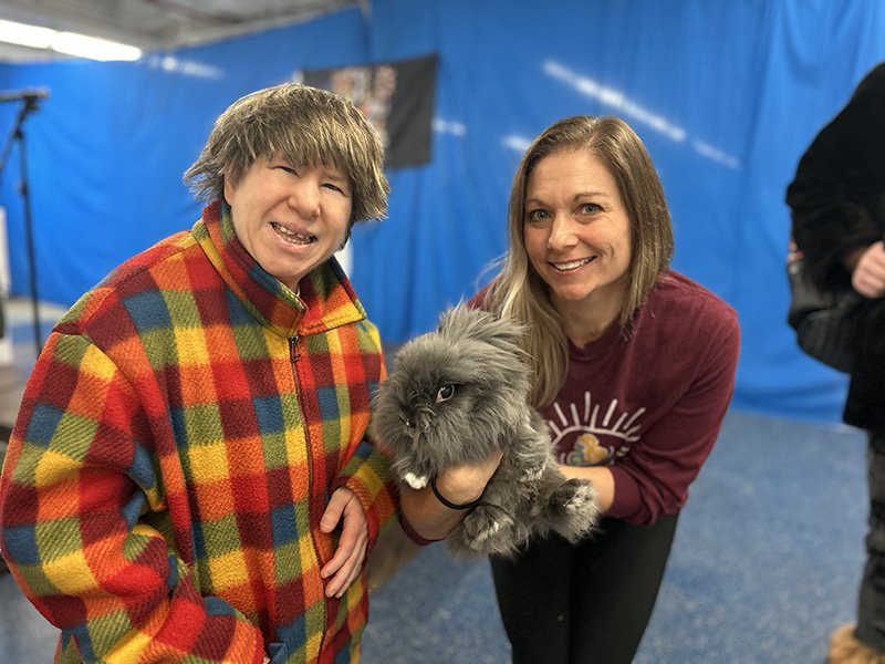 two women smiling, one is holding a rabbit