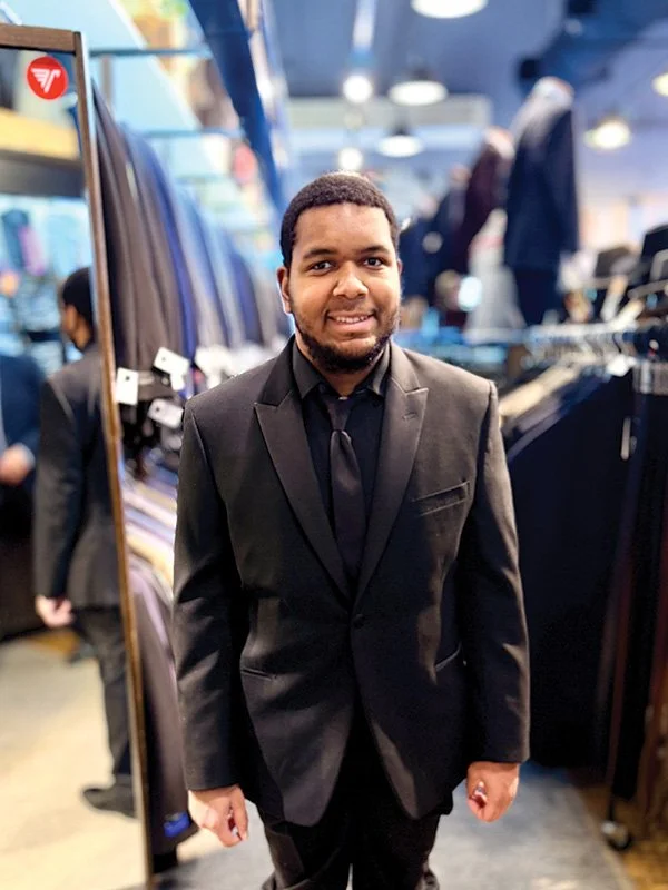 Man smiling dressed in suit working at men's clothing store