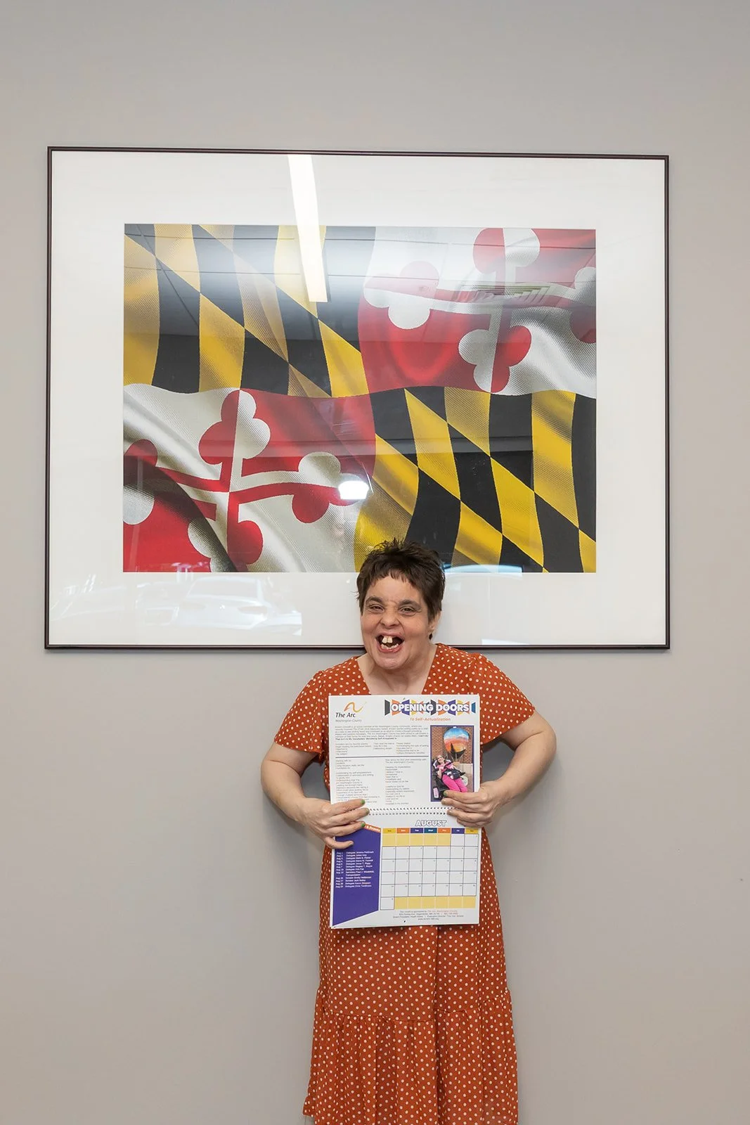 Jenny smiles with poster at The Arc of Washington County