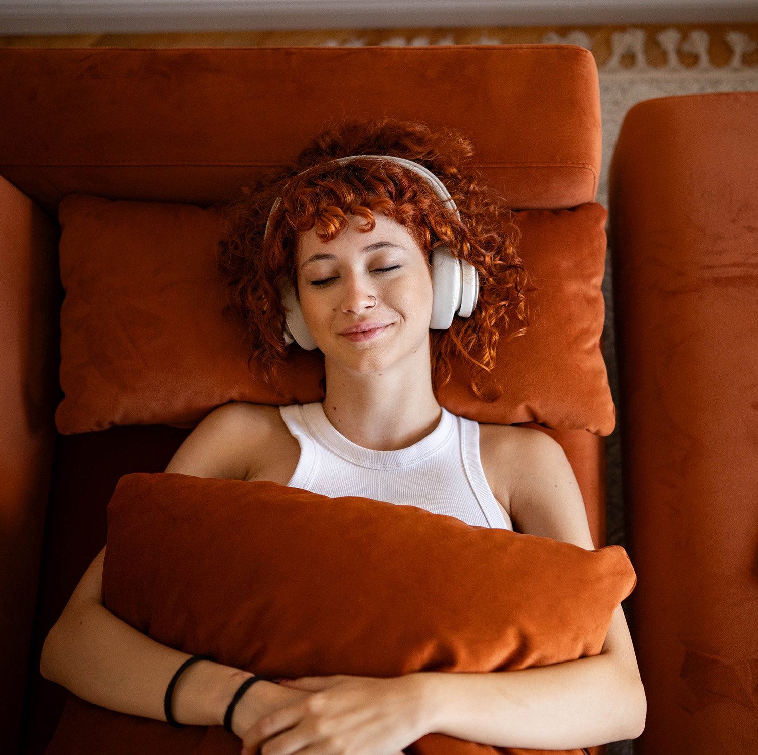 Woman smiling with eyes closed, lying on orange couch doing a KAP session.