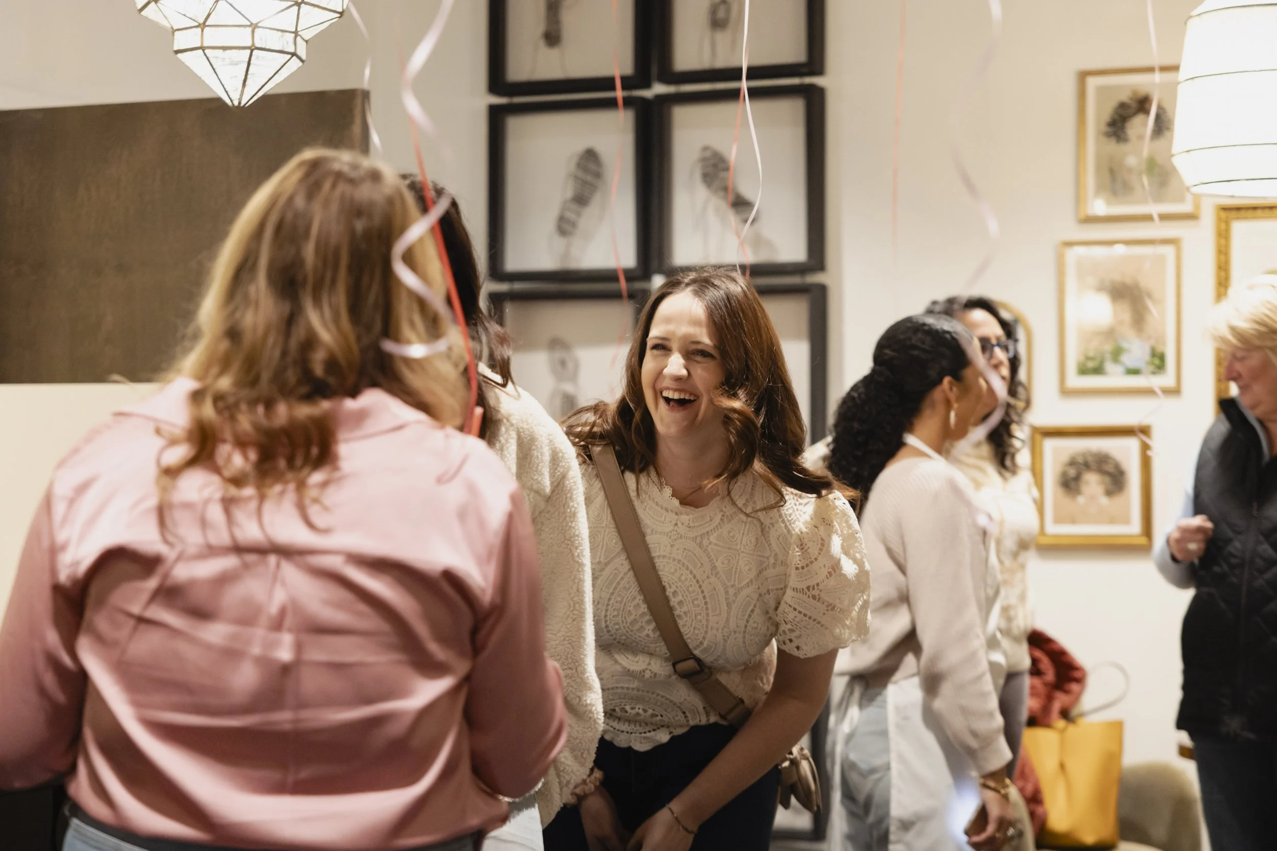 People socializing at a celebration or party with balloons and artwork on the walls.
