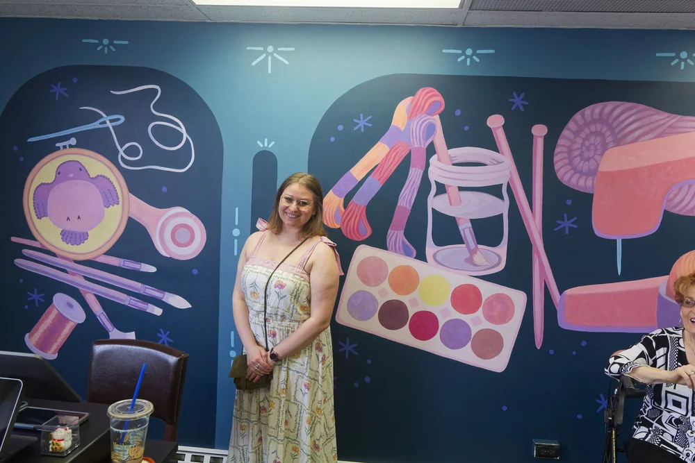Local artist posing with her mural masterpiece!