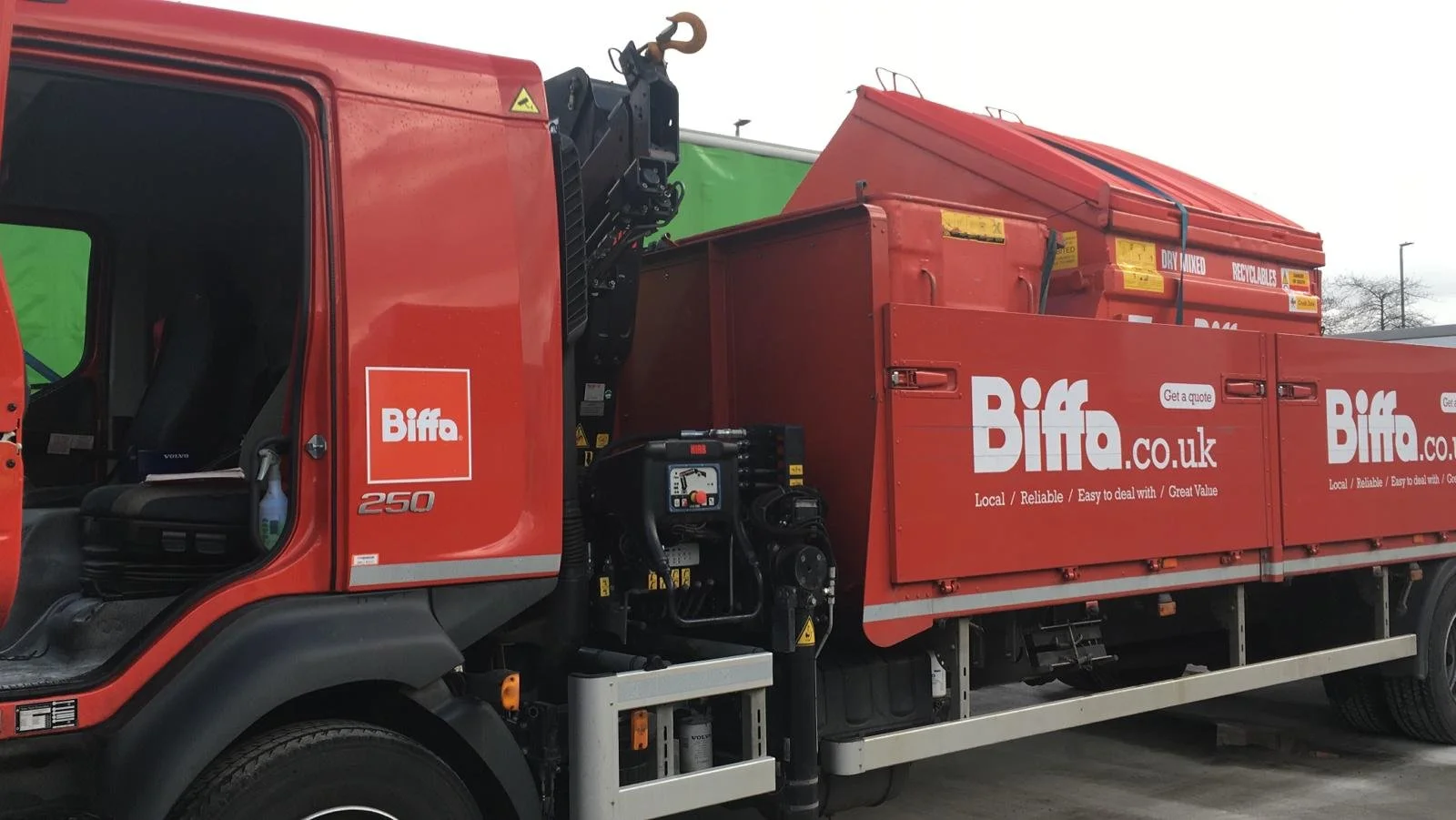 Red delivery truck with the logo and website of Biffa, a waste management company, on the side and top of the truck bed.