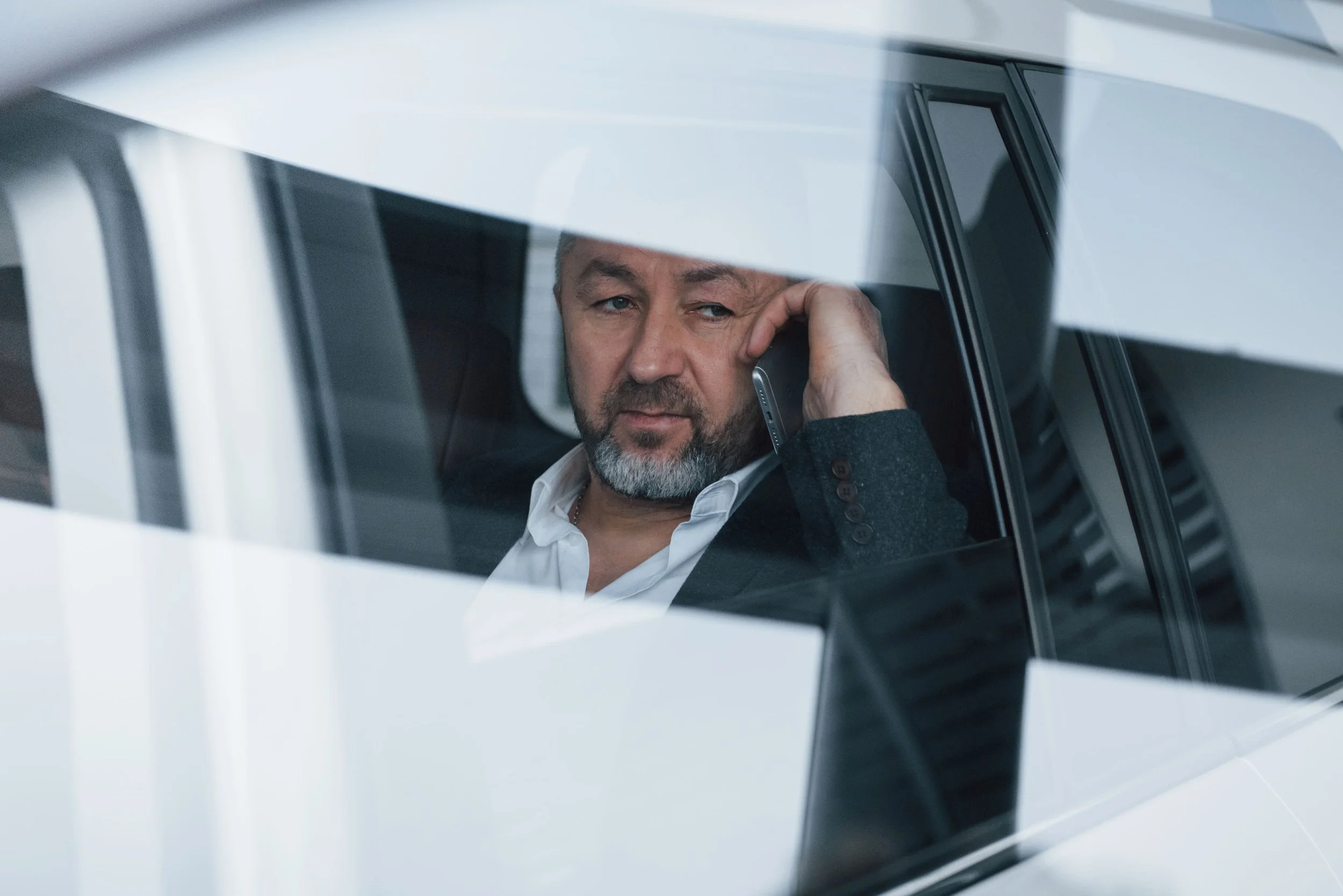 parece-cansado-reflexion-sobre-la-ventana-tener-una-llamada-de-negocios-mientras-esta-sentado-en-la-parte-trasera-del-automovil-de-lujo-moderno.jpg
