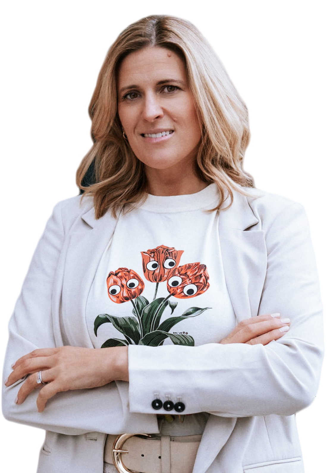 A woman with blonde, wavy hair, wearing a white blazer and a white t-shirt with a graphic of orange tulips with googly eyes, standing with arms crossed against a black background.