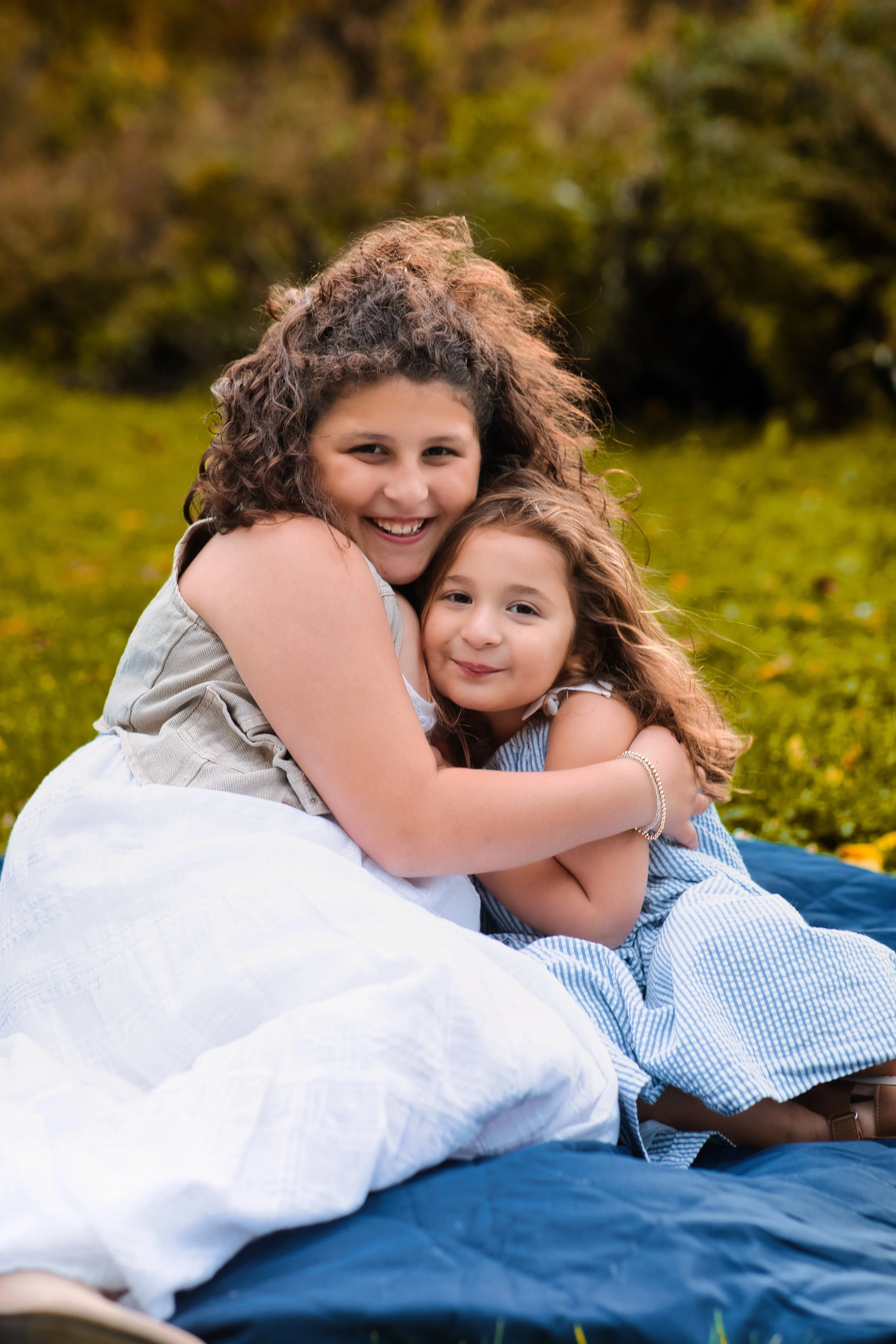 Rochester, NY sibling portrait of two young girls hugging and smiling outdoors in fall