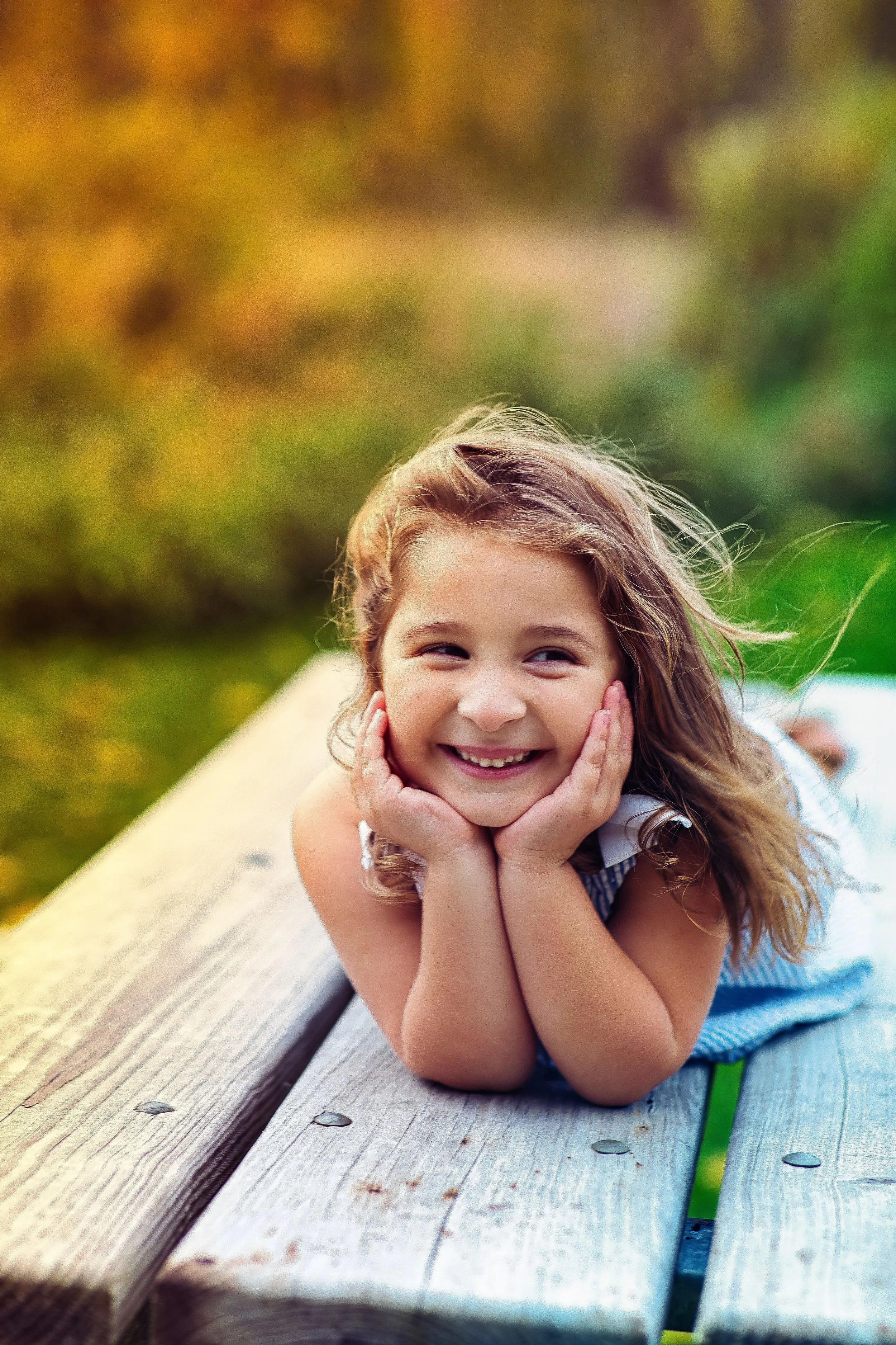 Rochester, NY portrait of a young girl smiling on a bench outdoors in fall