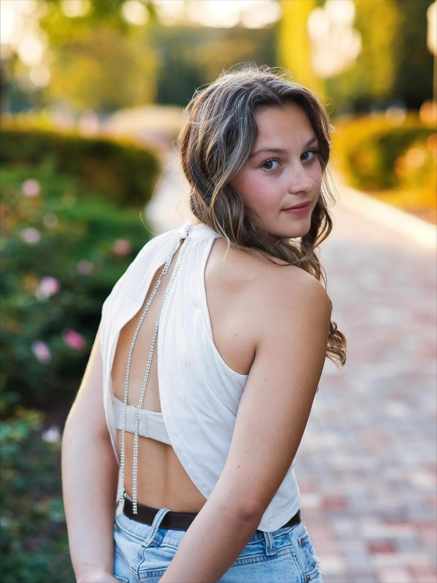 Senior girl in white backless top looking over shoulder at Memorial Art Gallery gardens, Rochester NY senior pictures