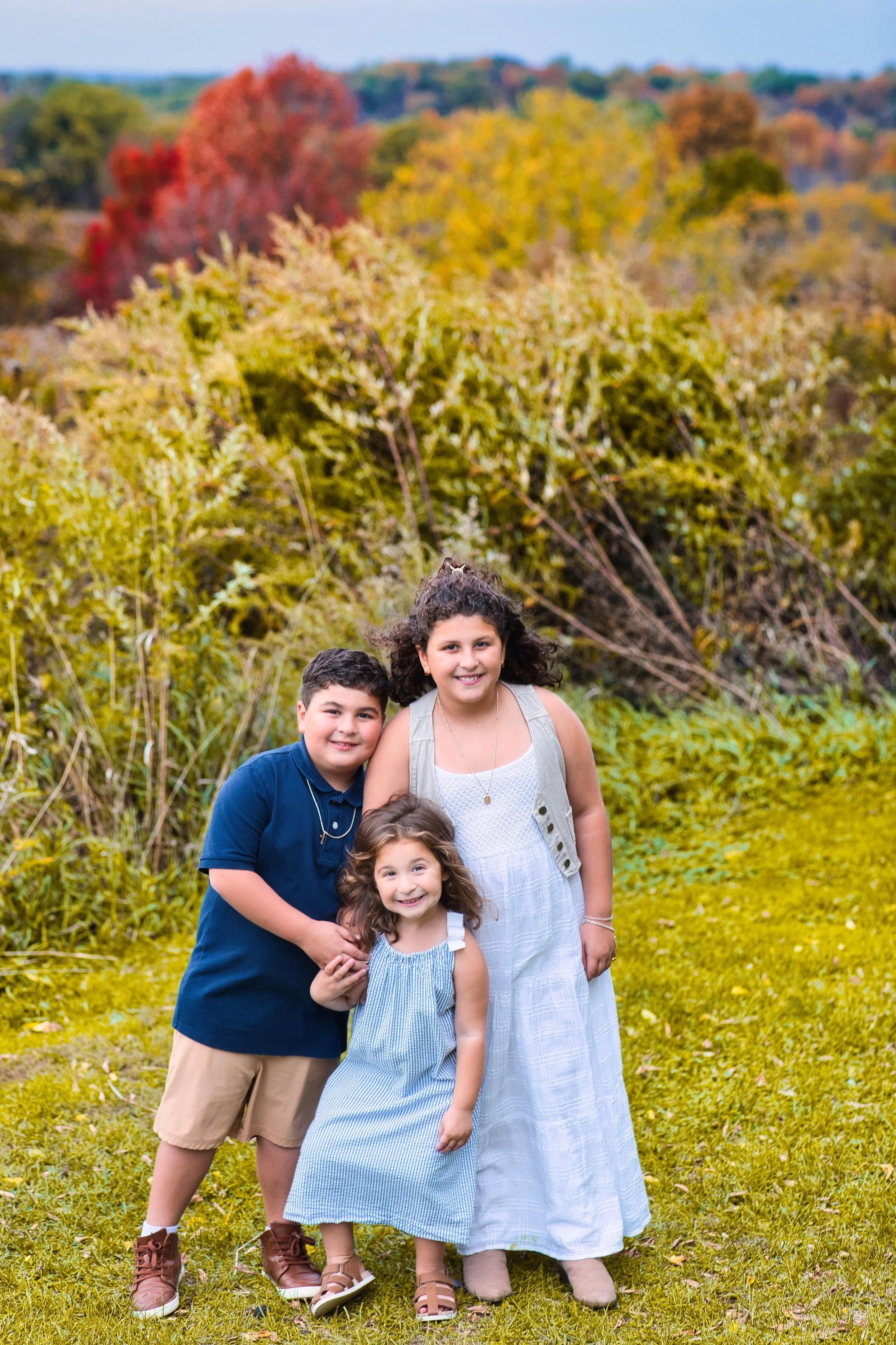 Rochester, NY family portrait of three children standing together in a fall field
