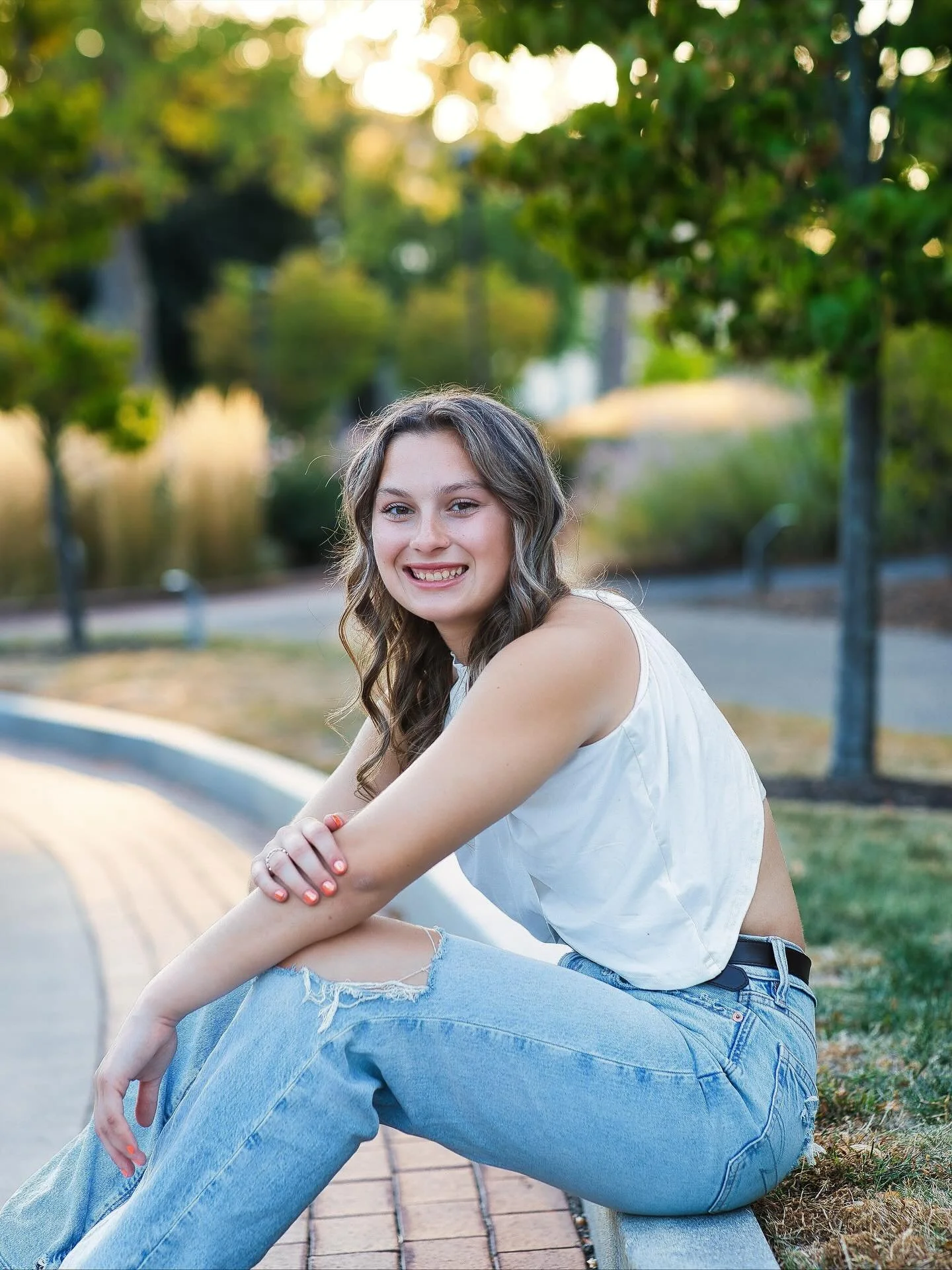 Senior girl in white top smiling seated outdoors at Memorial Art Gallery Rochester NY senior photos