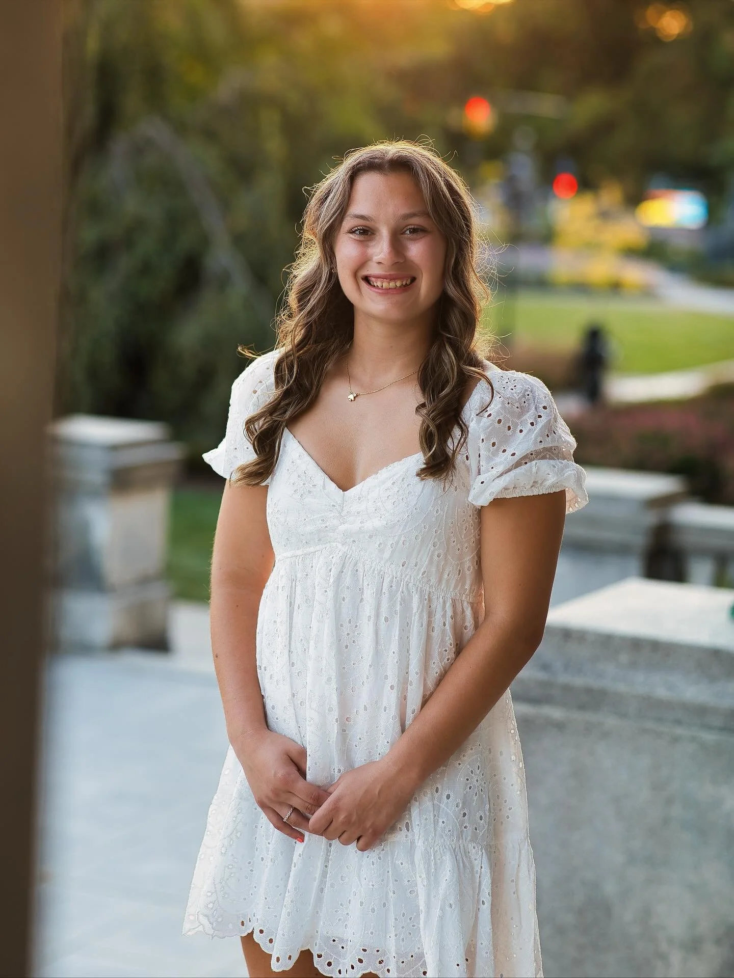 Senior girl in white dress smiling outdoors at Memorial Art Gallery grounds, classic senior portraits Rochester NY