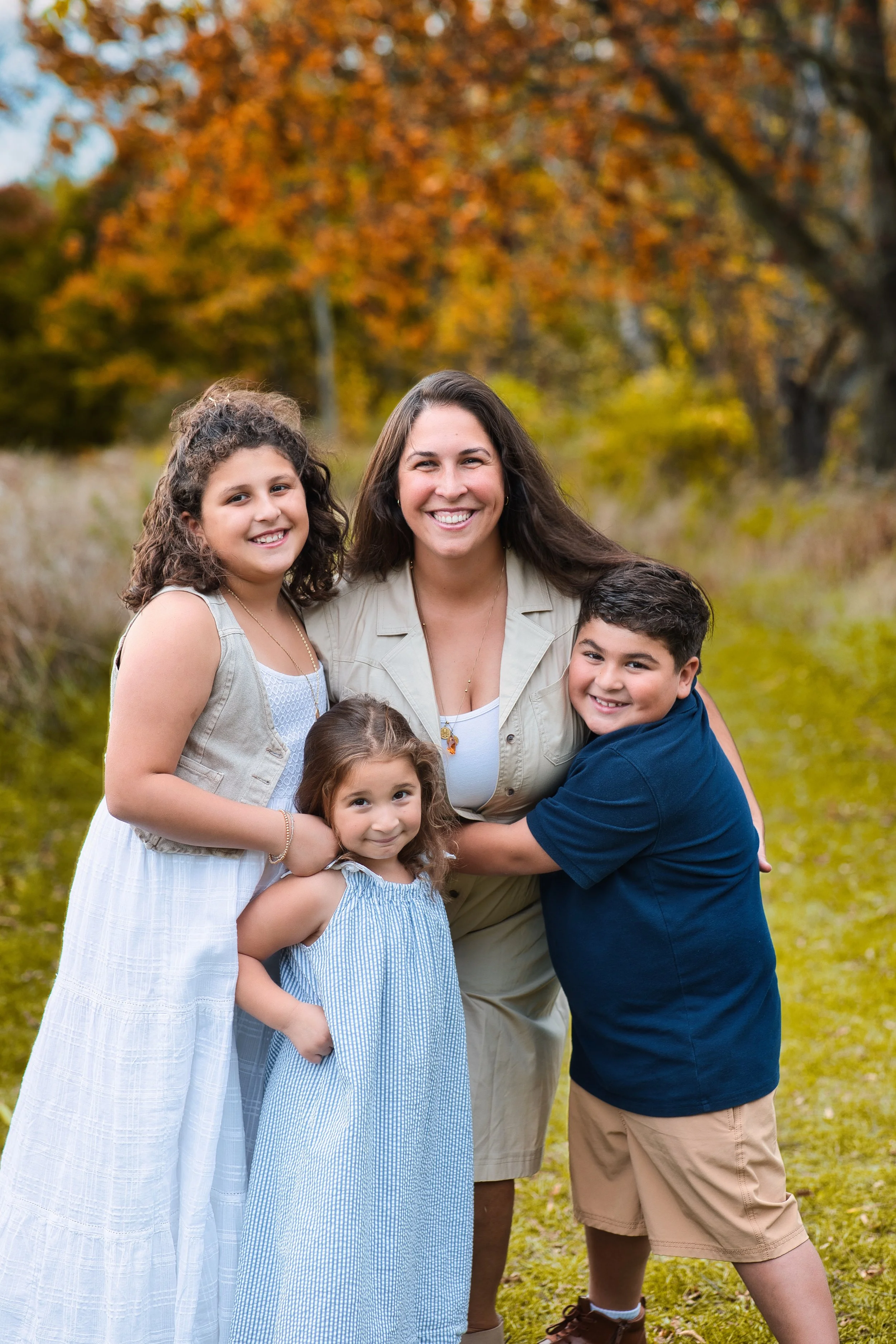 Rochester, NY family portrait of a mother with three children smiling together outdoors