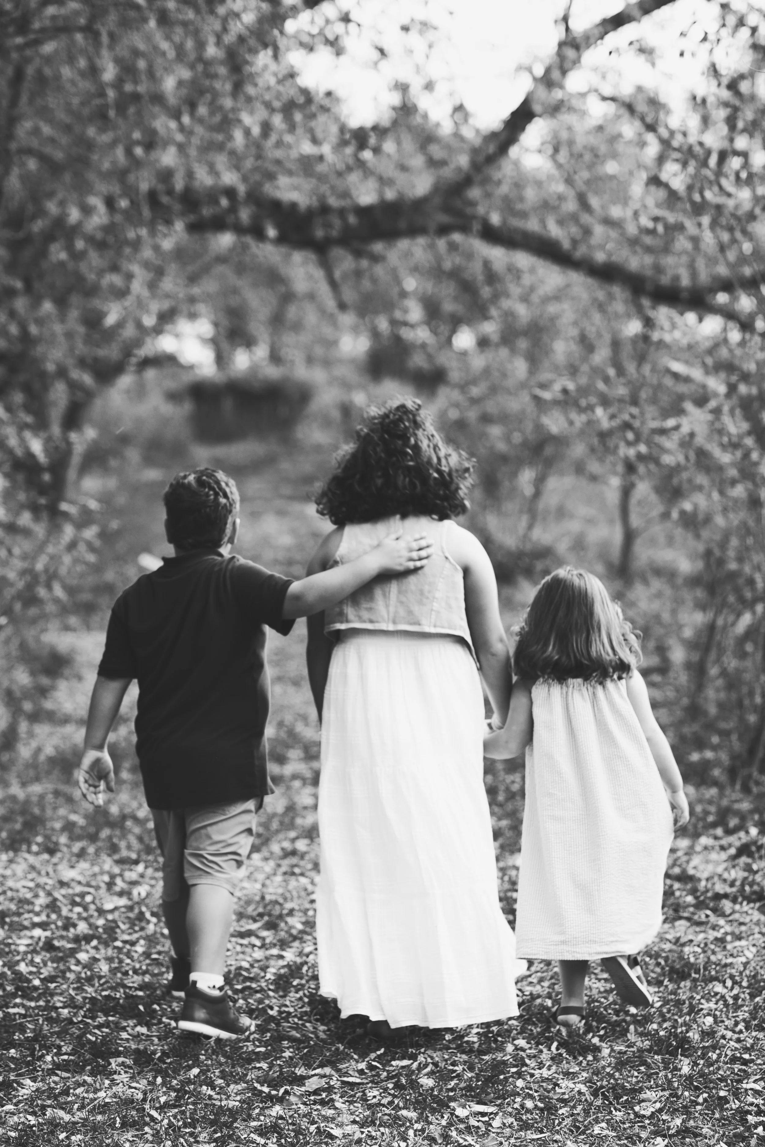 Rochester, NY black and white family portrait of a three children walking away together outdoors
