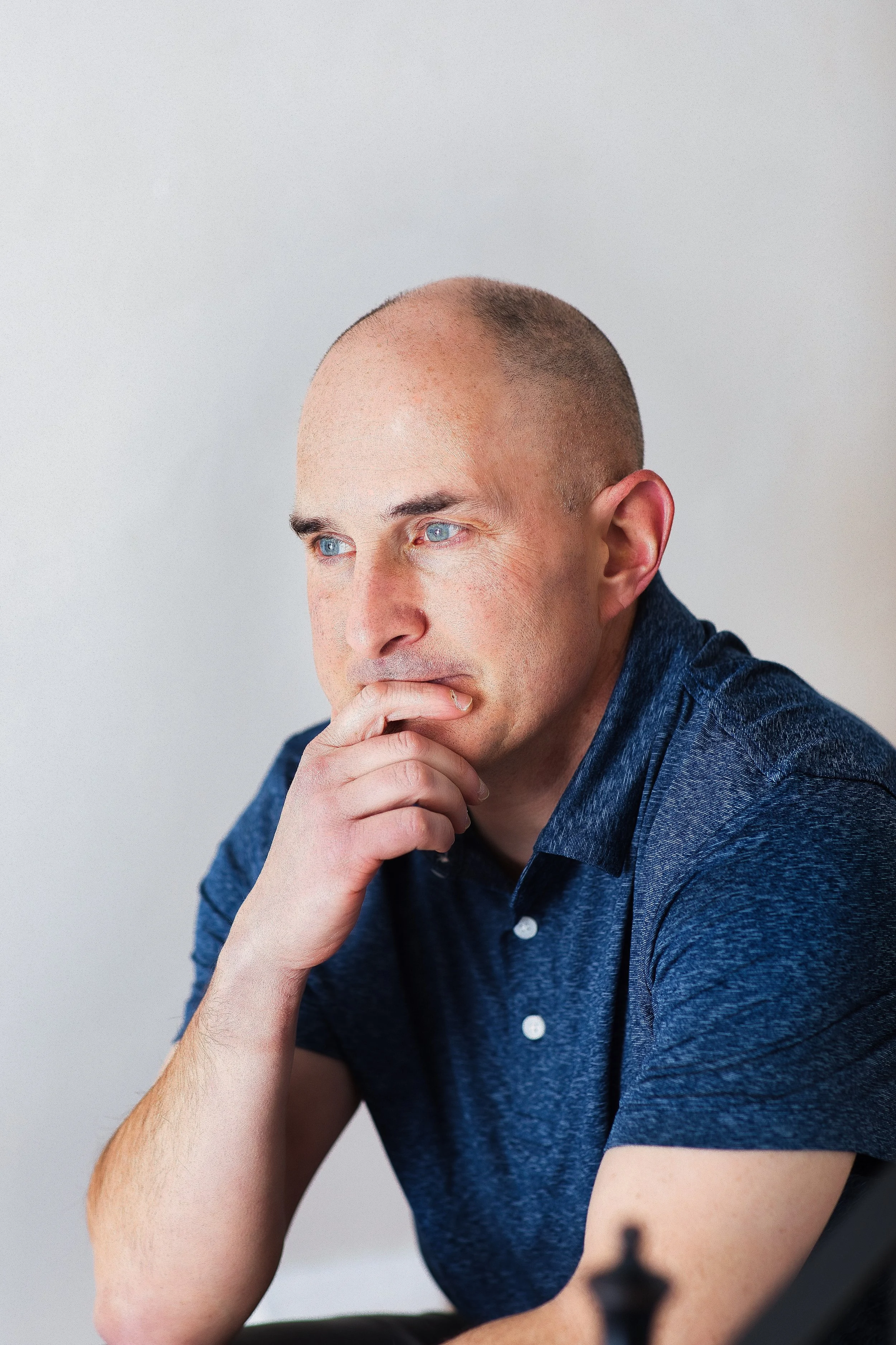 Close-up professional headshot of man with hand on chin, natural light portrait