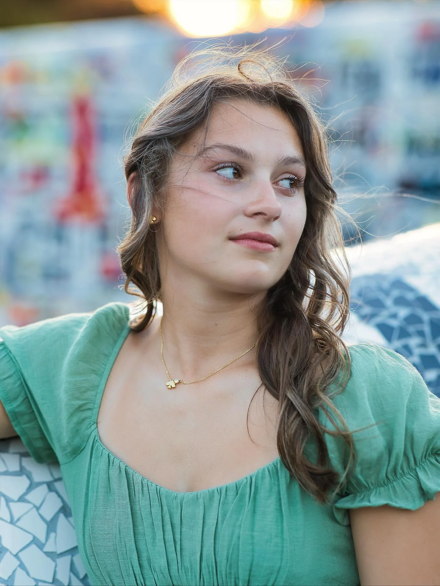 Close-up senior portrait of girl in green top against colorful graffiti wall, urban senior photography Rochester NY