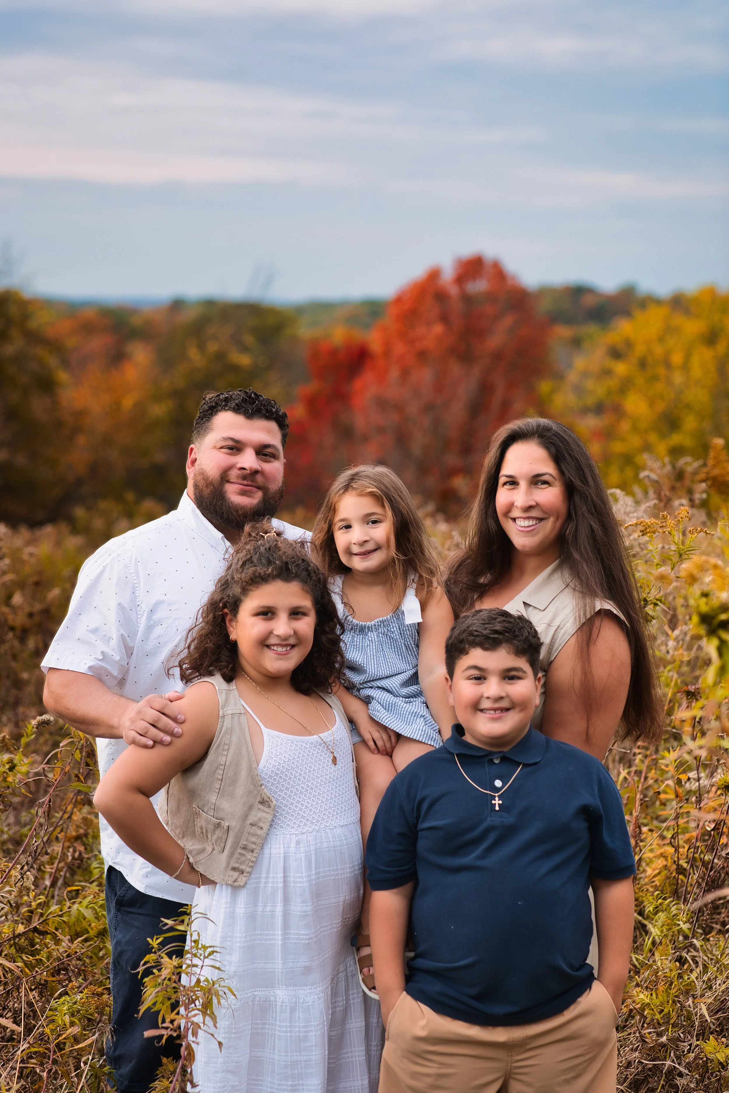 Rochester, NY family portrait of parents and children posed together with fall foliage