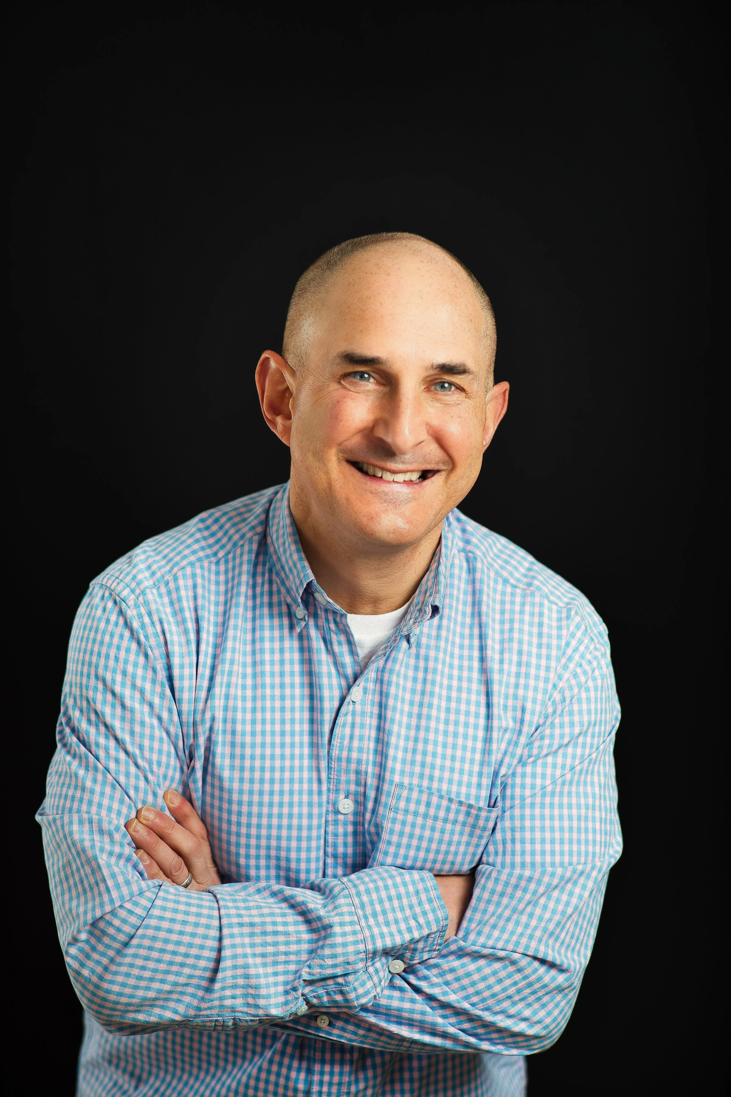 Studio-style professional LinkedIn headshot of man smiling against black background