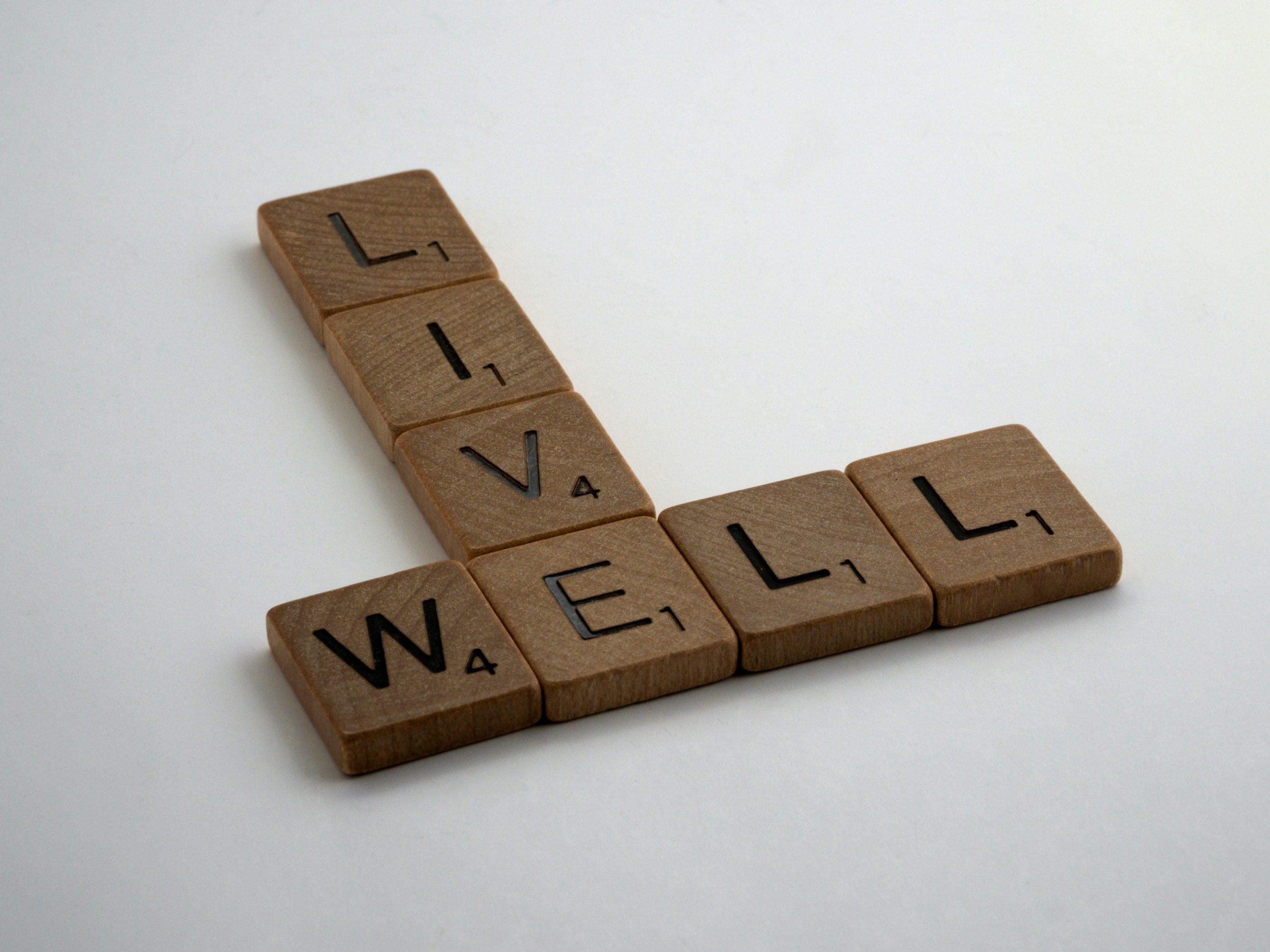 Wooden Scrabble tiles spelling the word 'LOVE' arranged on a white surface.