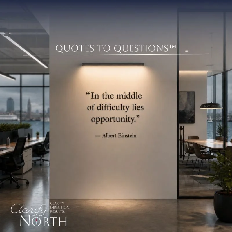 Office space with a quote on the wall by Albert Einstein, stating 'In the middle of difficulty lies opportunity.' The space has large windows, a view of the city and water, and modern furniture.