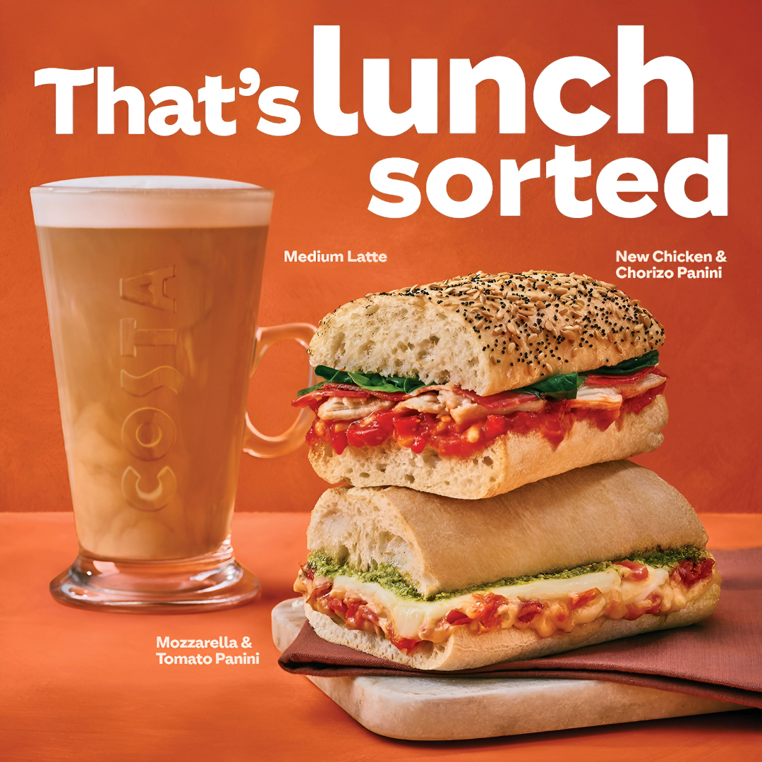 Advertisement featuring a medium latte in a branded glass, a chicken and chorizo panini, and a mozzarella and tomato panini on a marble board, with the text 'That's lunch sorted' on an orange background.