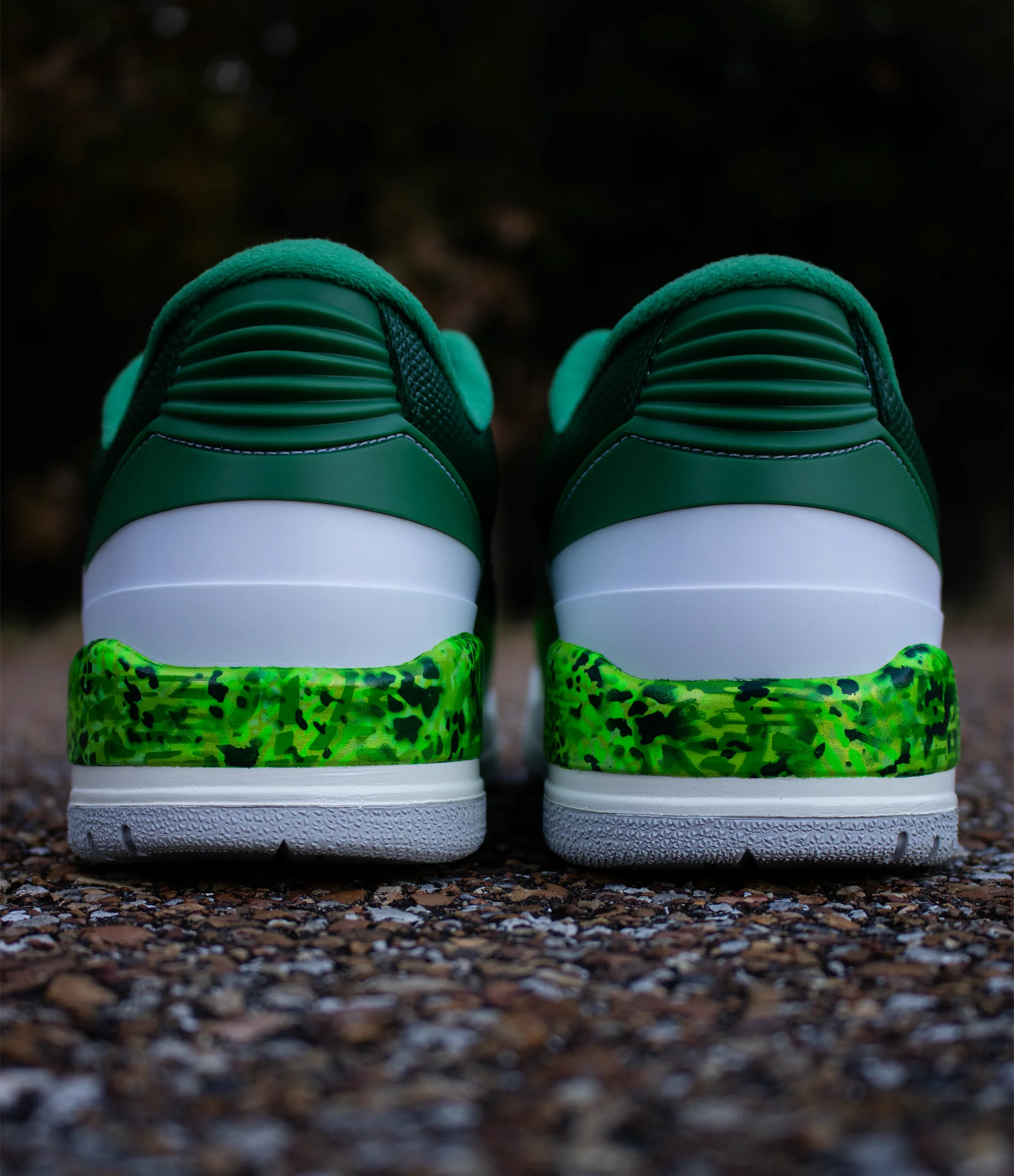 Close-up of green and white sneakers on a gravel surface, with a dark blurred background.