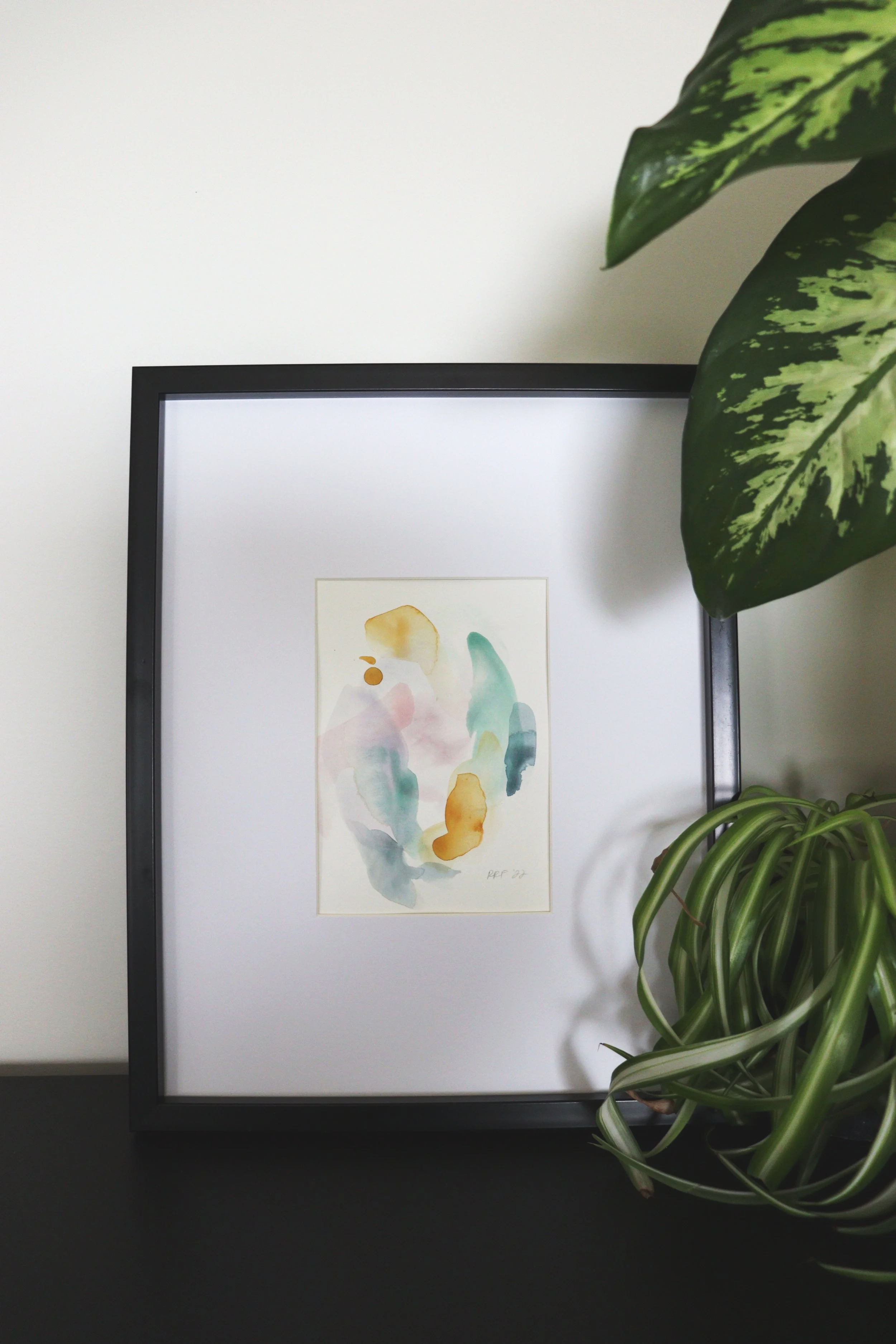 An abstract gouache artwork painted in soothing neutral hues, with flowing shapes and layered textures that create a sense of calm, balance, and natural warmth, framed in a modern black frame