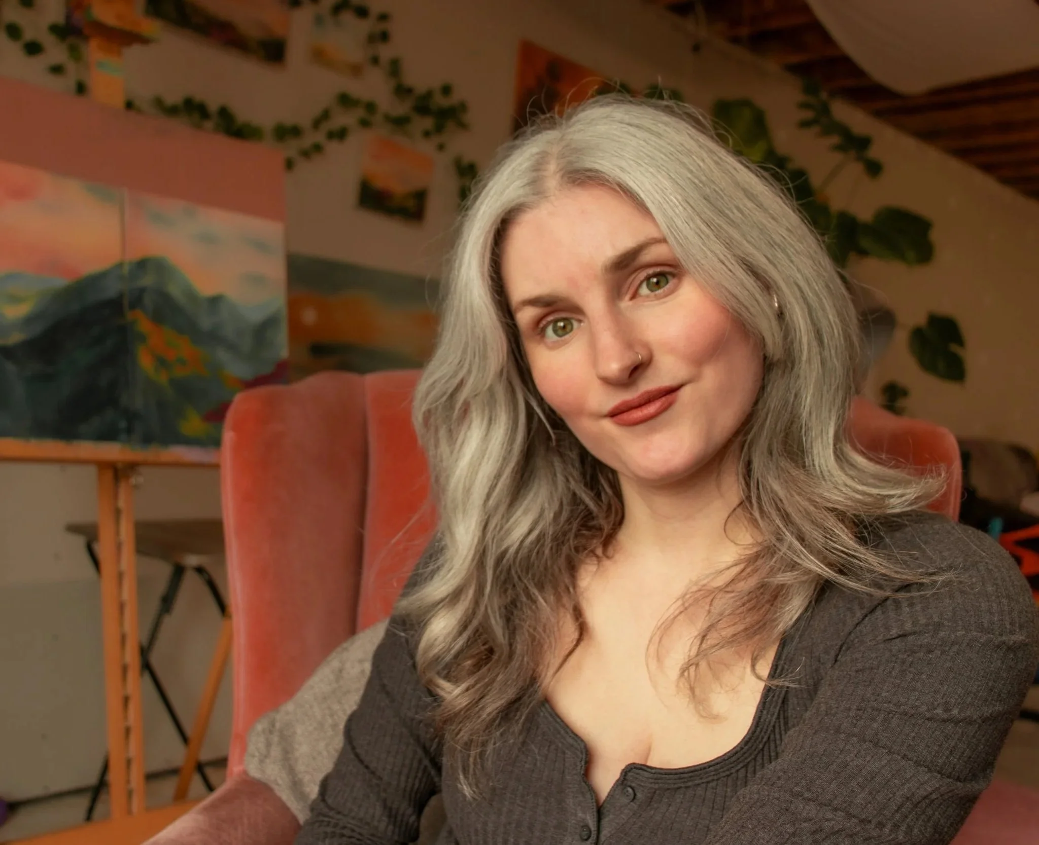 The photo shows the artist smiling in her studio, with the layered, textured painting displayed behind her.