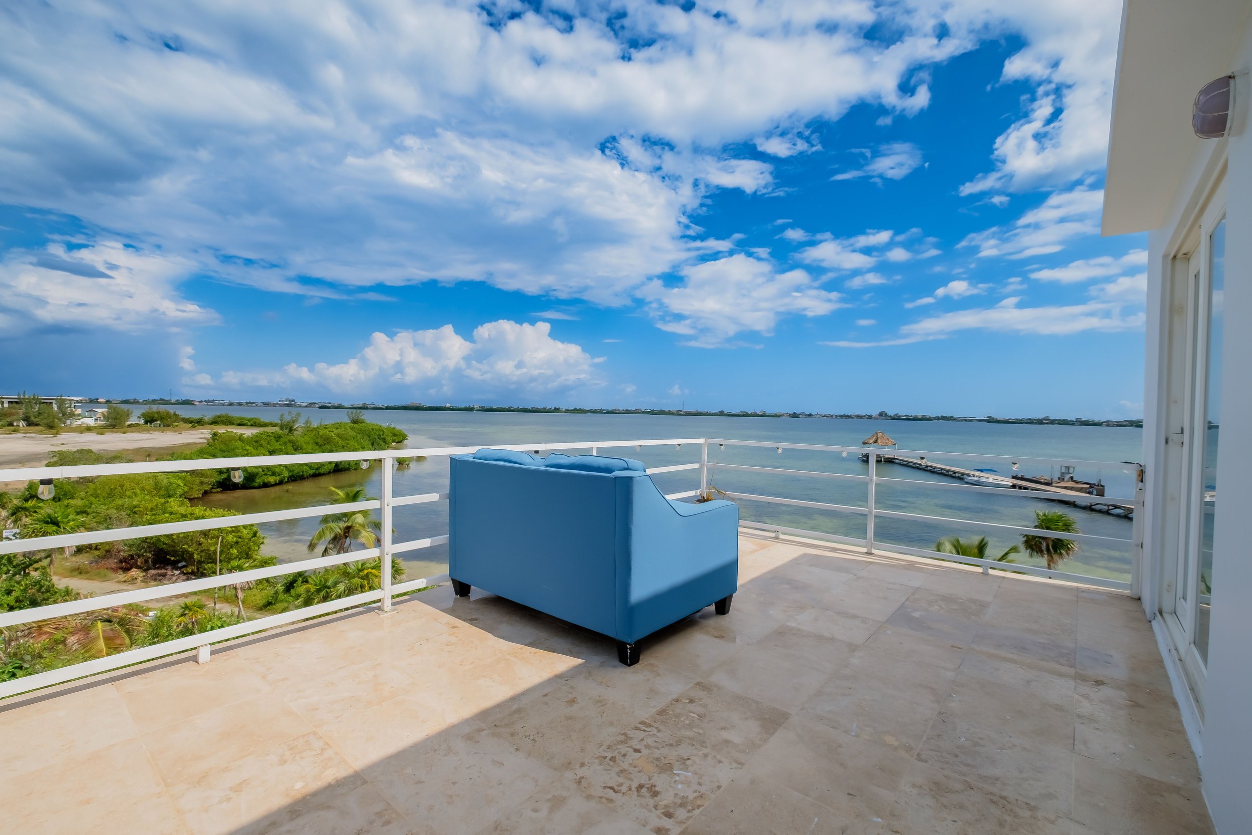 Terrace with a blue couch overlooking ocean and sky