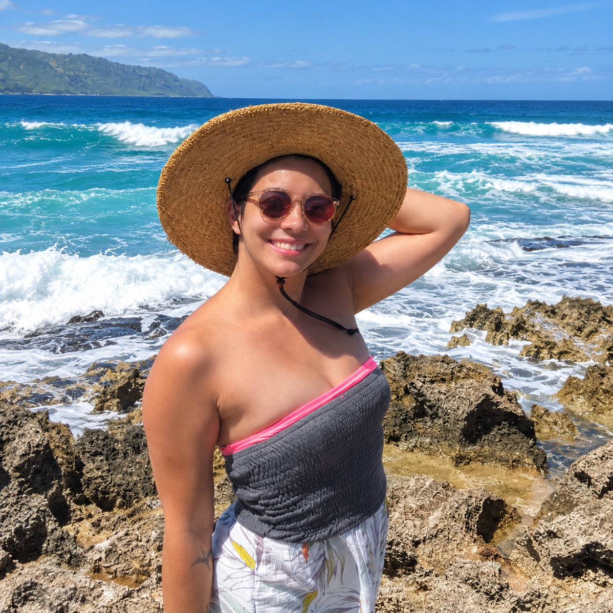 Dr. Iwalani Crush smiling beside the ocean in a sun hat.