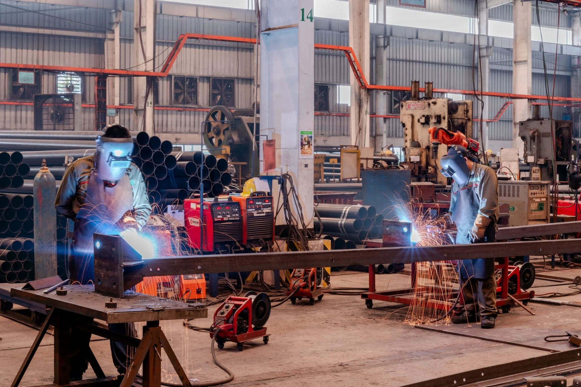 two fabricators work on automotive parts in a manufacturing setting