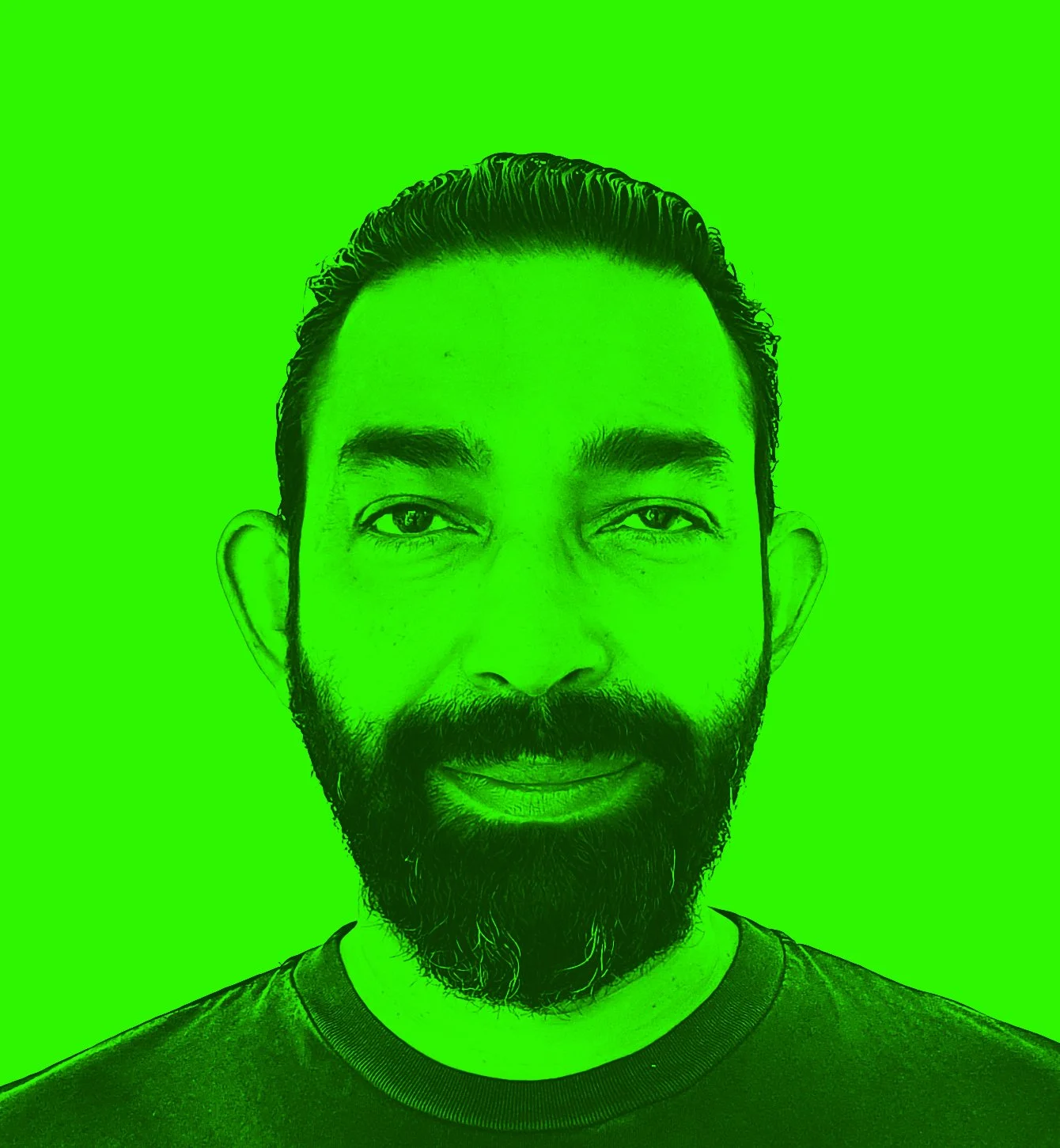 A bearded man with slicked-back hair, smiling, against a bright green background.