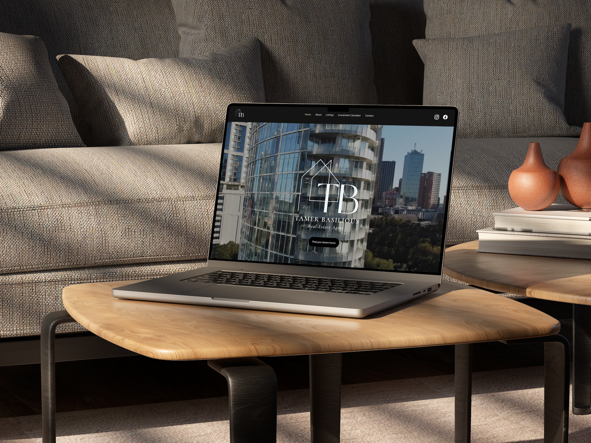 A laptop on a wooden coffee table displaying a real estate website with images of modern high-rise buildings in a cityscape. The table is in a living room with a beige fabric sofa and an arrangement of three terracotta vases and a stack of white books on a side table.