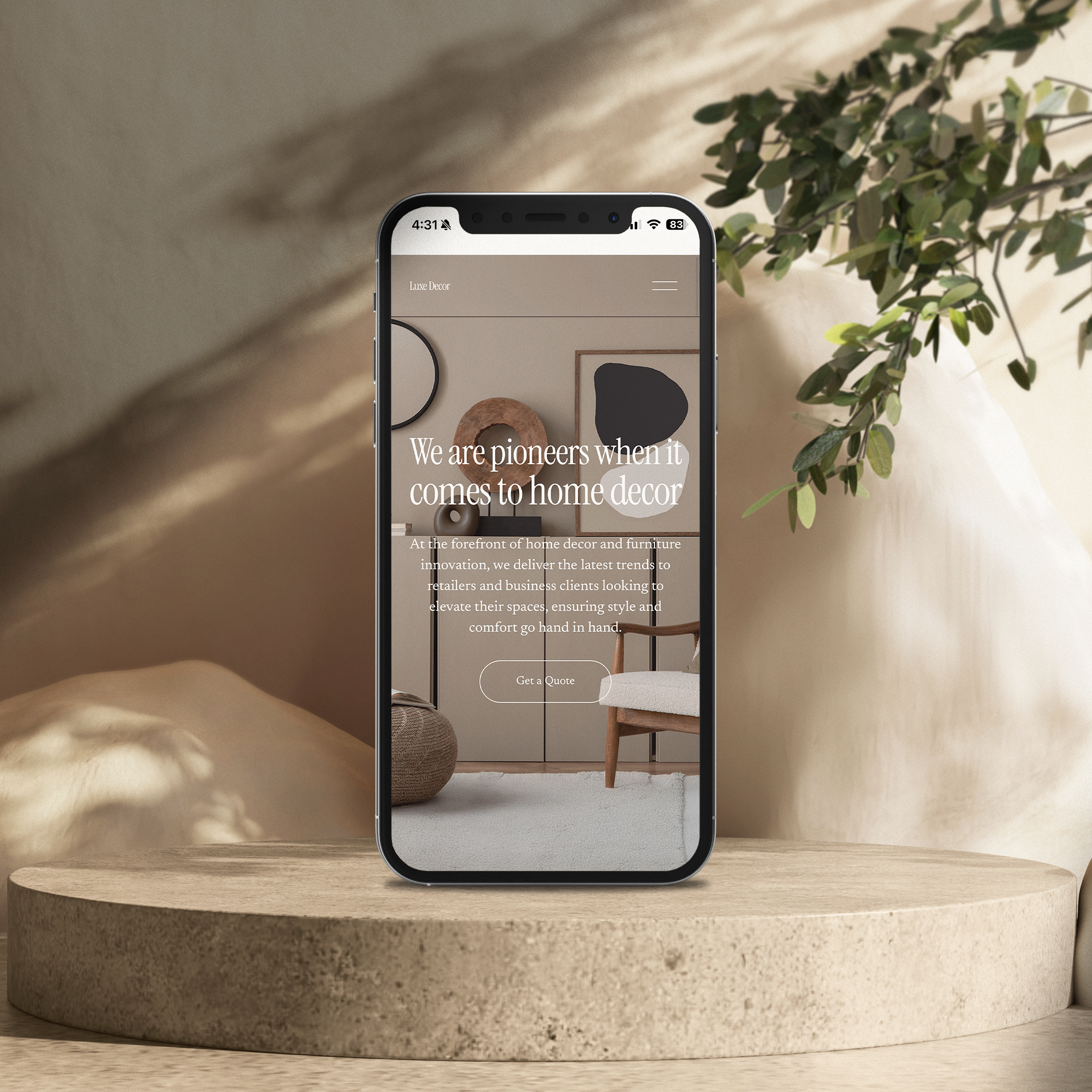 A smartphone displaying a home decor website stands on a beige circular pedestal, with a green plant on the right side and shadows cast on a beige wall in the background.