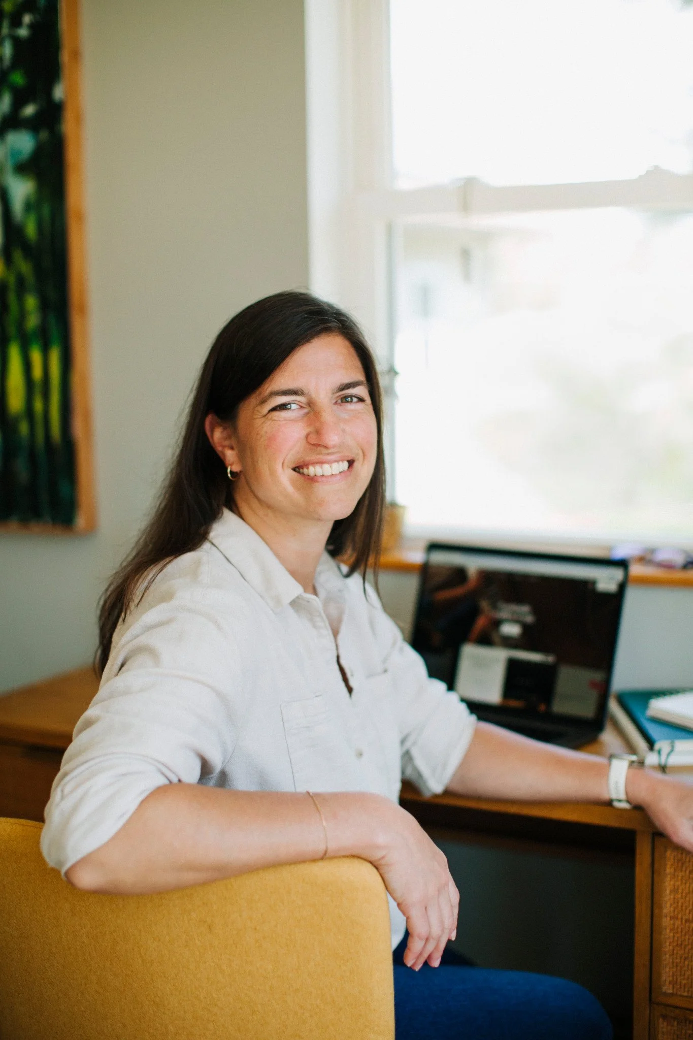Nana Potenza with long dark hair smiling and sitting at a desk with a computer.