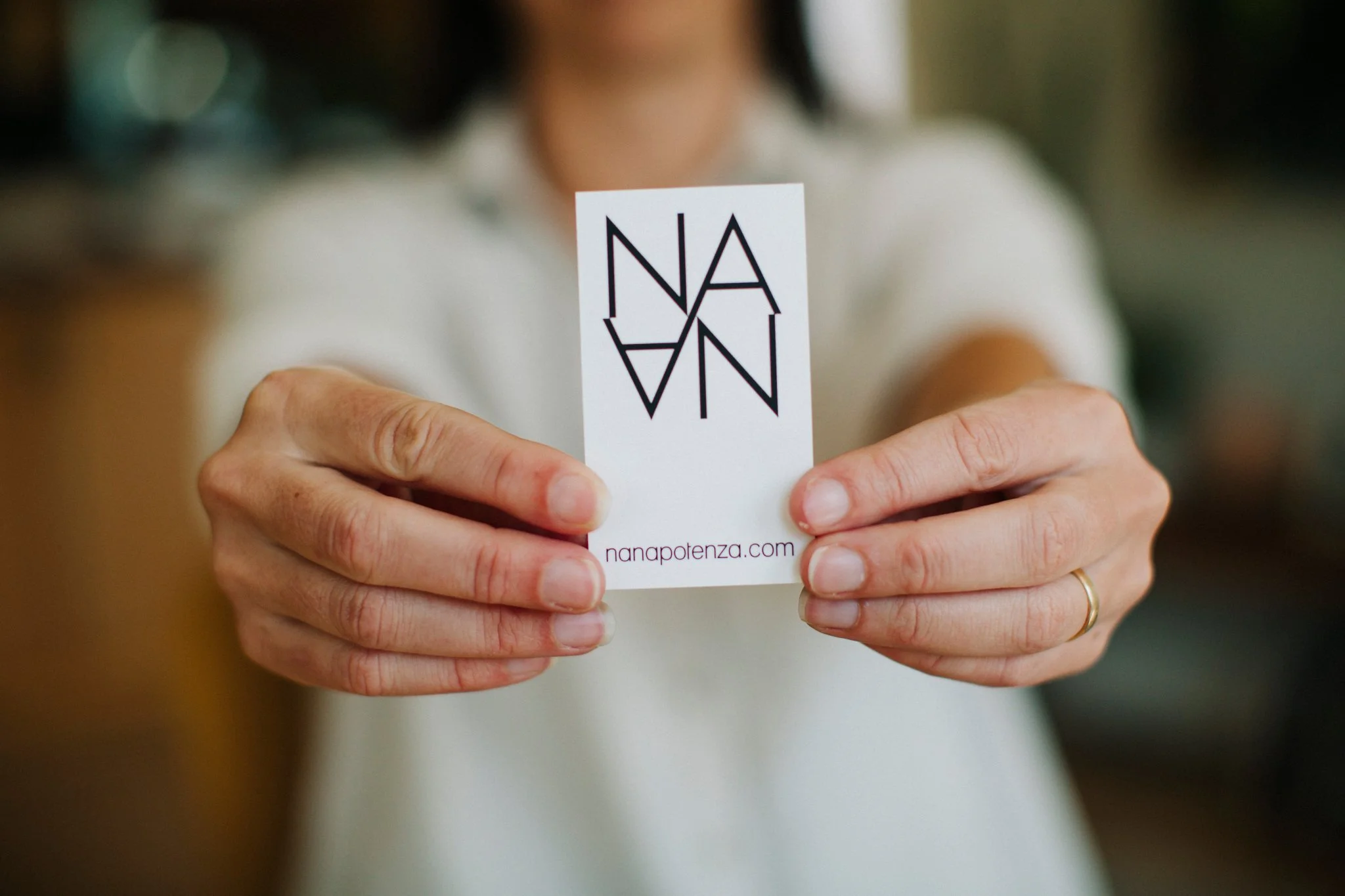 Nana Potenza holding her business card with the logo and URL 'nanapotenza.com'.