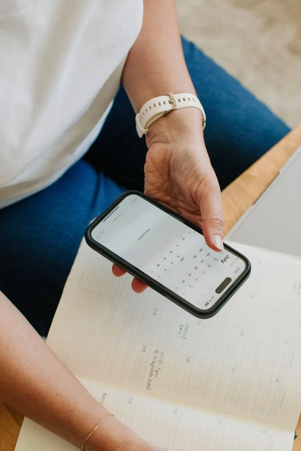 Nana sitting at a table using a smartphone with a calendar app open.