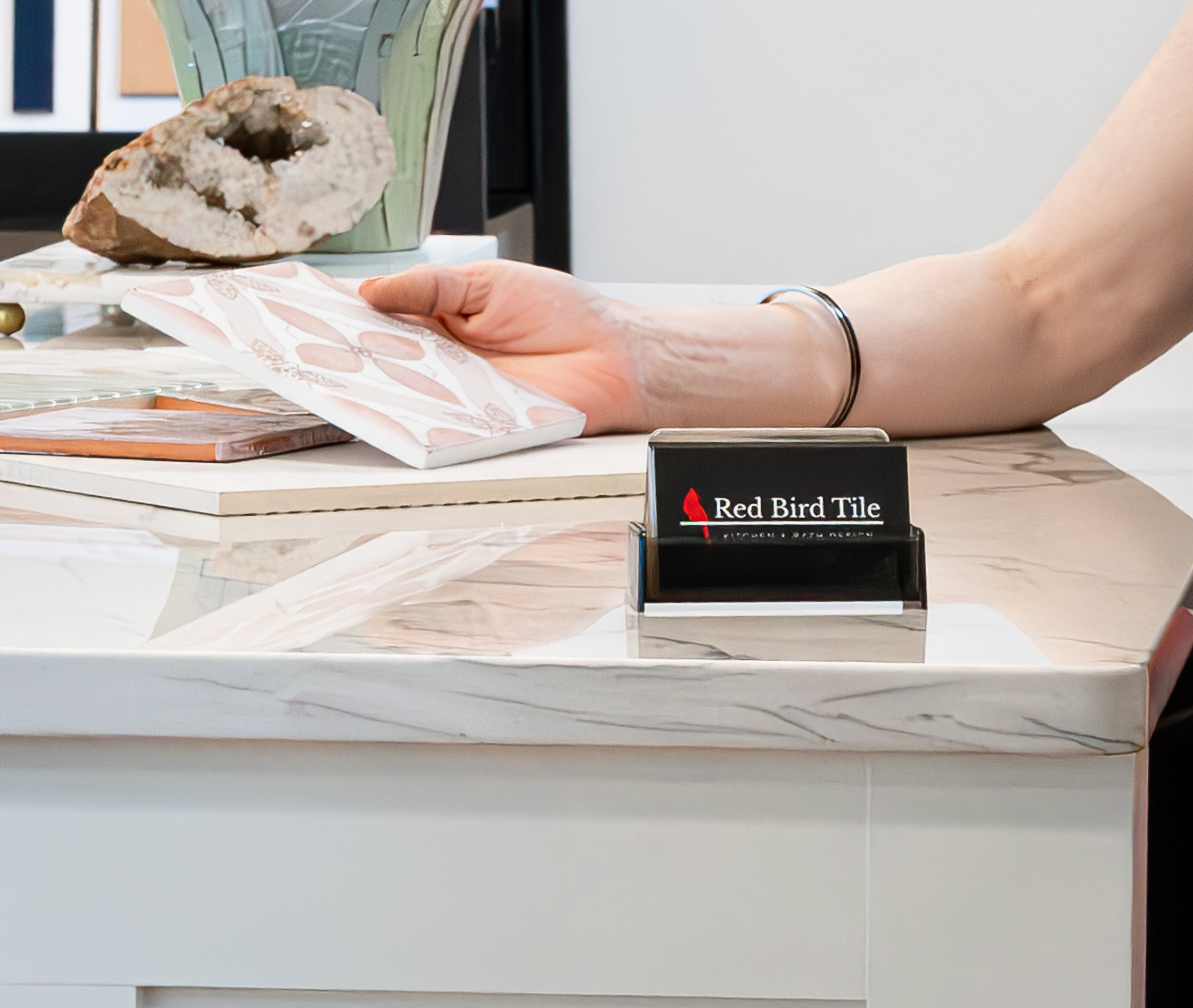 Display of various tiles on a  desk along with Red Bird Tile business cards.