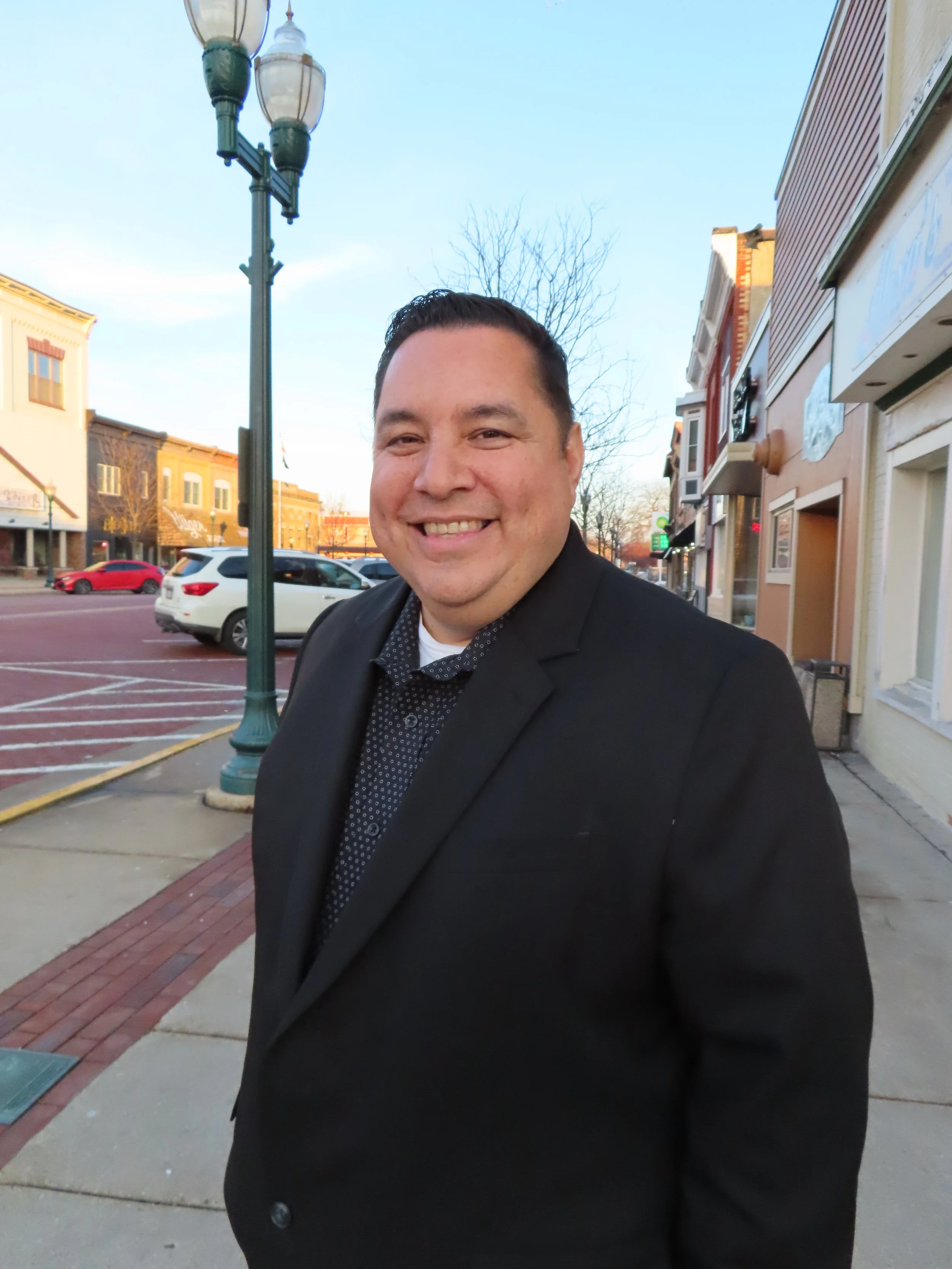 Luis Solis in Downtown Delavan brick street with multiple buildings. Photo by Sara Dominguez
