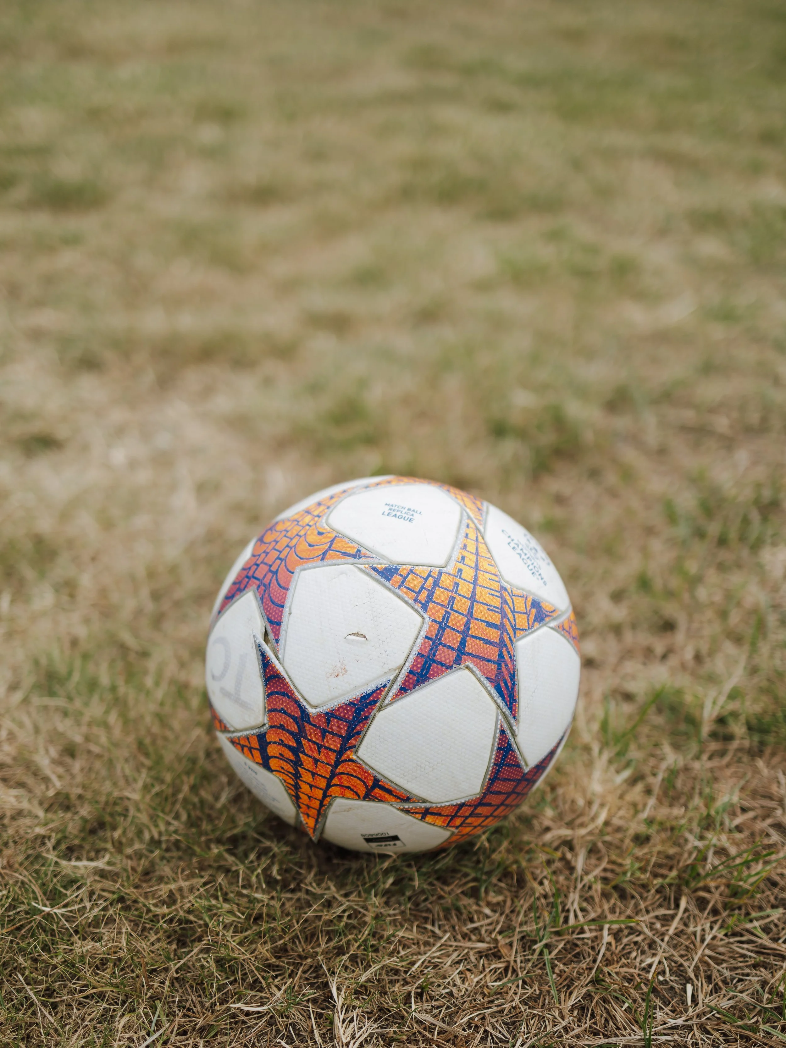 A soccer ball resting on dry grass field.