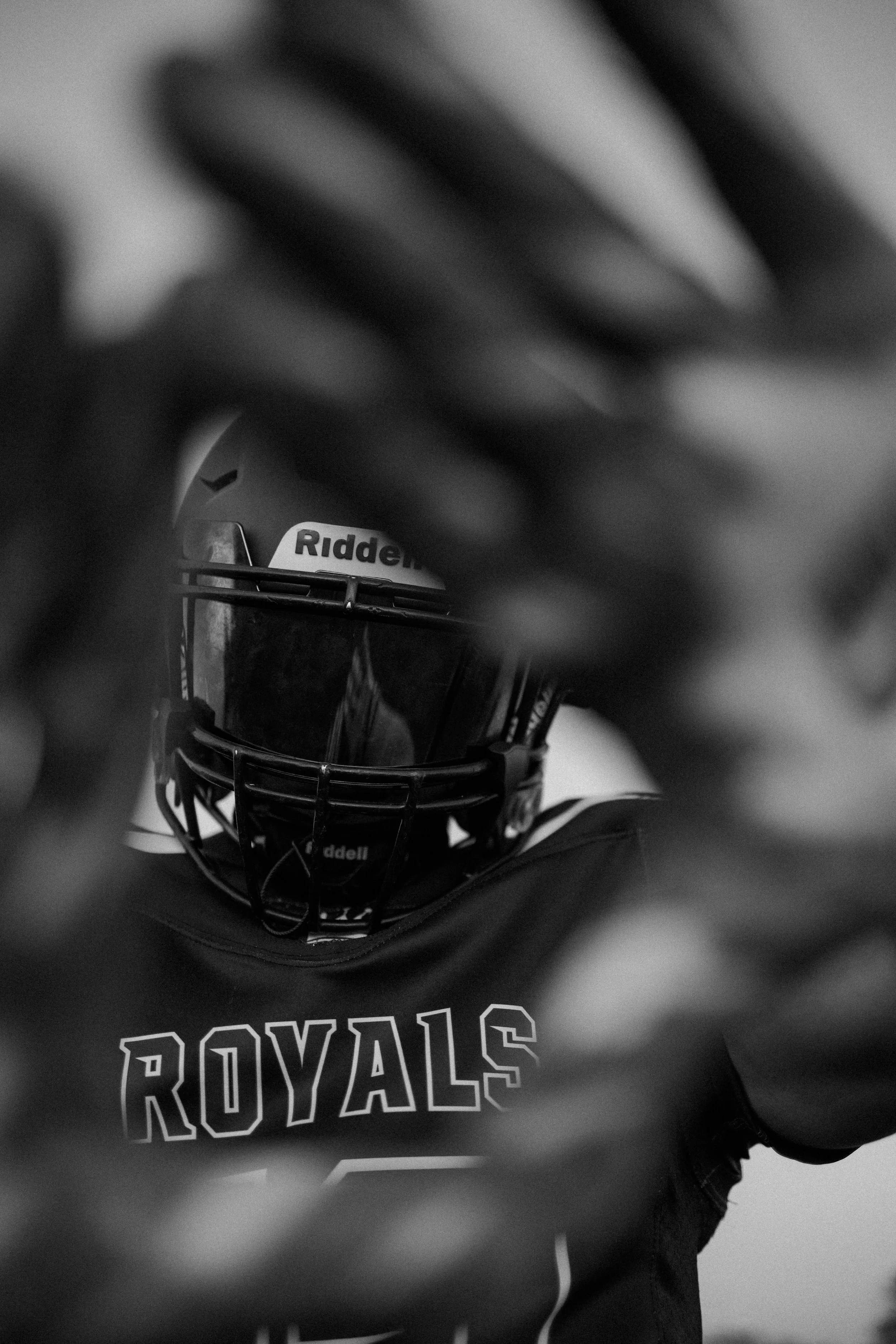 Close-up of a person wearing a hockey helmet with a cage, with the brand name Riddell visible, and a jersey that says Royals.